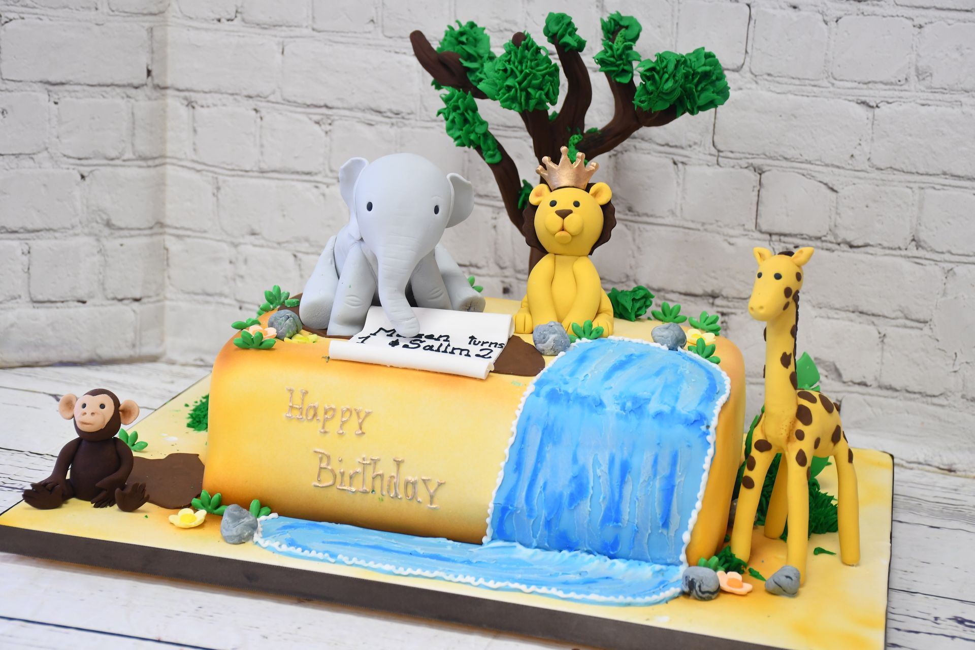 A birthday cake with animals and a waterfall on it