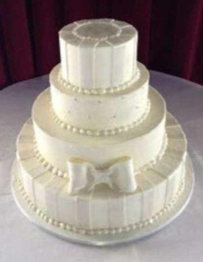 A white wedding cake with a bow on it