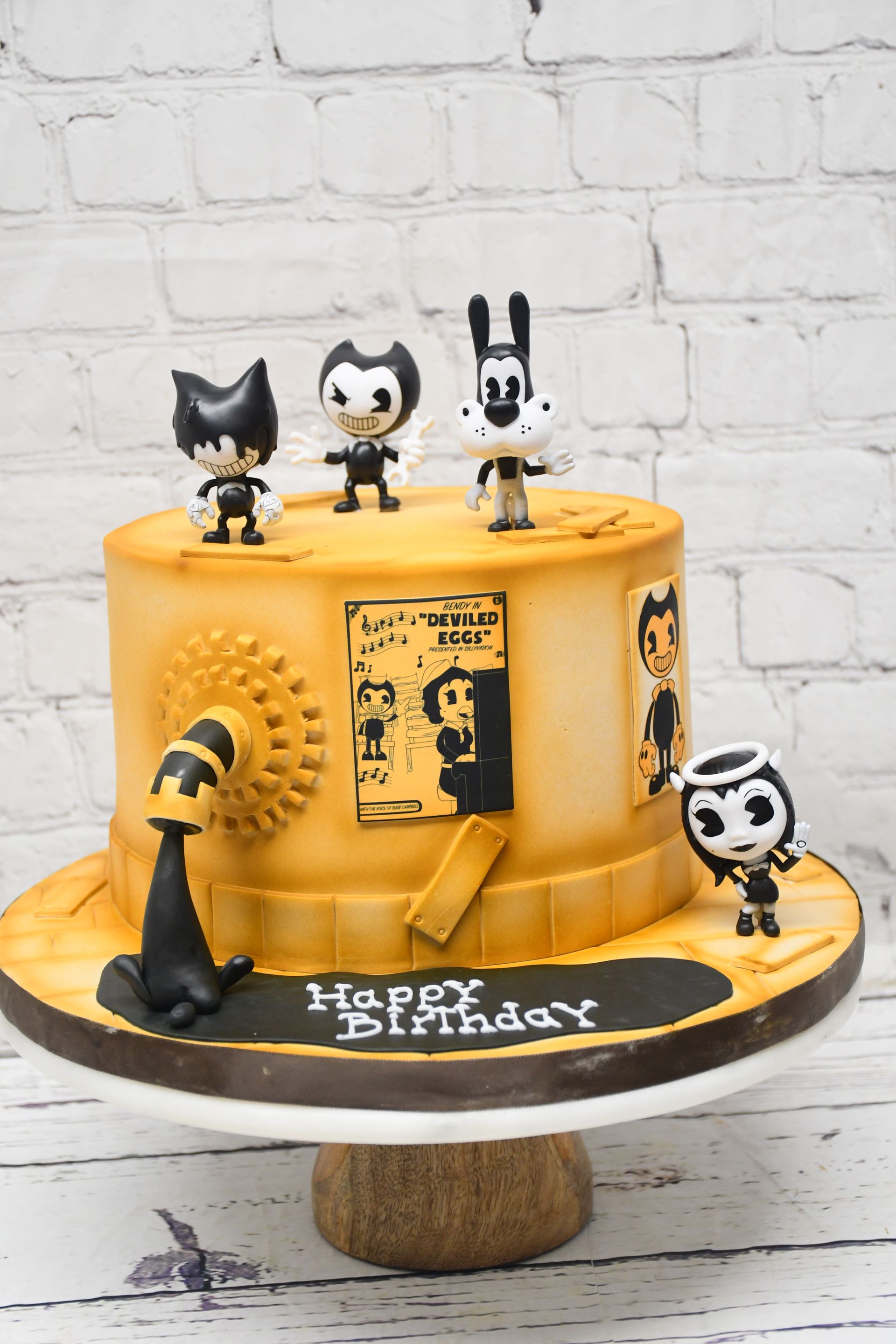 A birthday cake with bendy and the ink machine characters on it