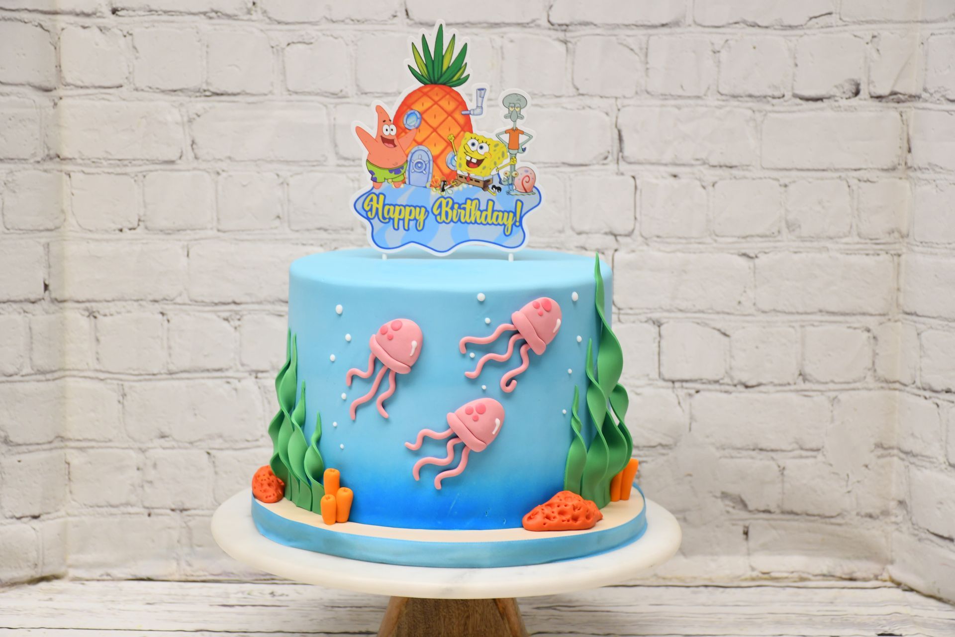 A blue cake with spongebob squarepants and jellyfish on it