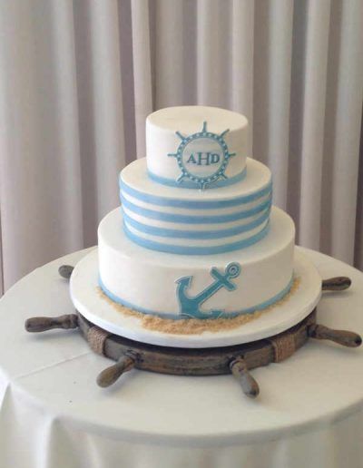 A three tiered cake with an anchor on top of it