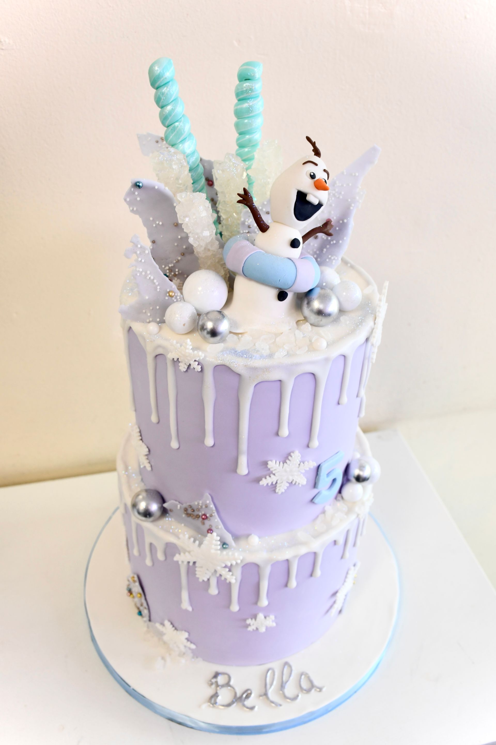 A purple and white cake with a snowman on top of it.