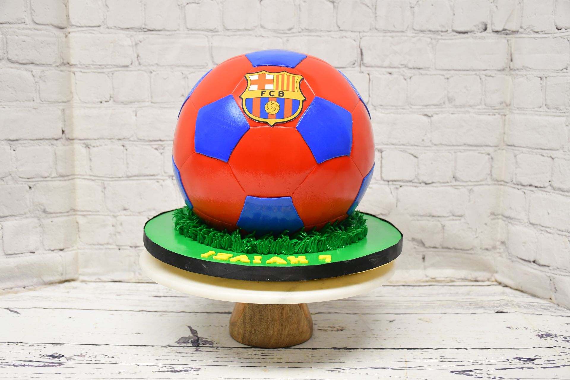 A cake in the shape of a soccer ball is on a cake stand.