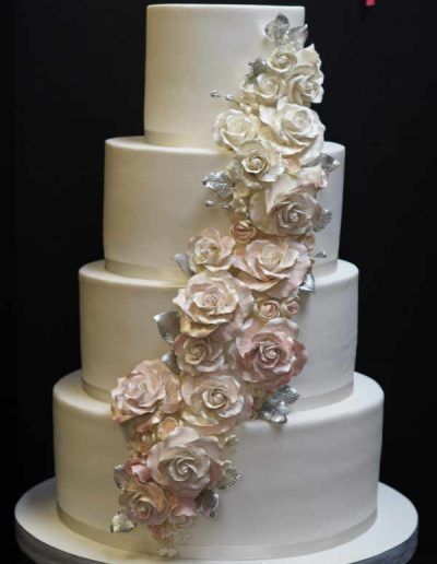 A white wedding cake with pink roses on it