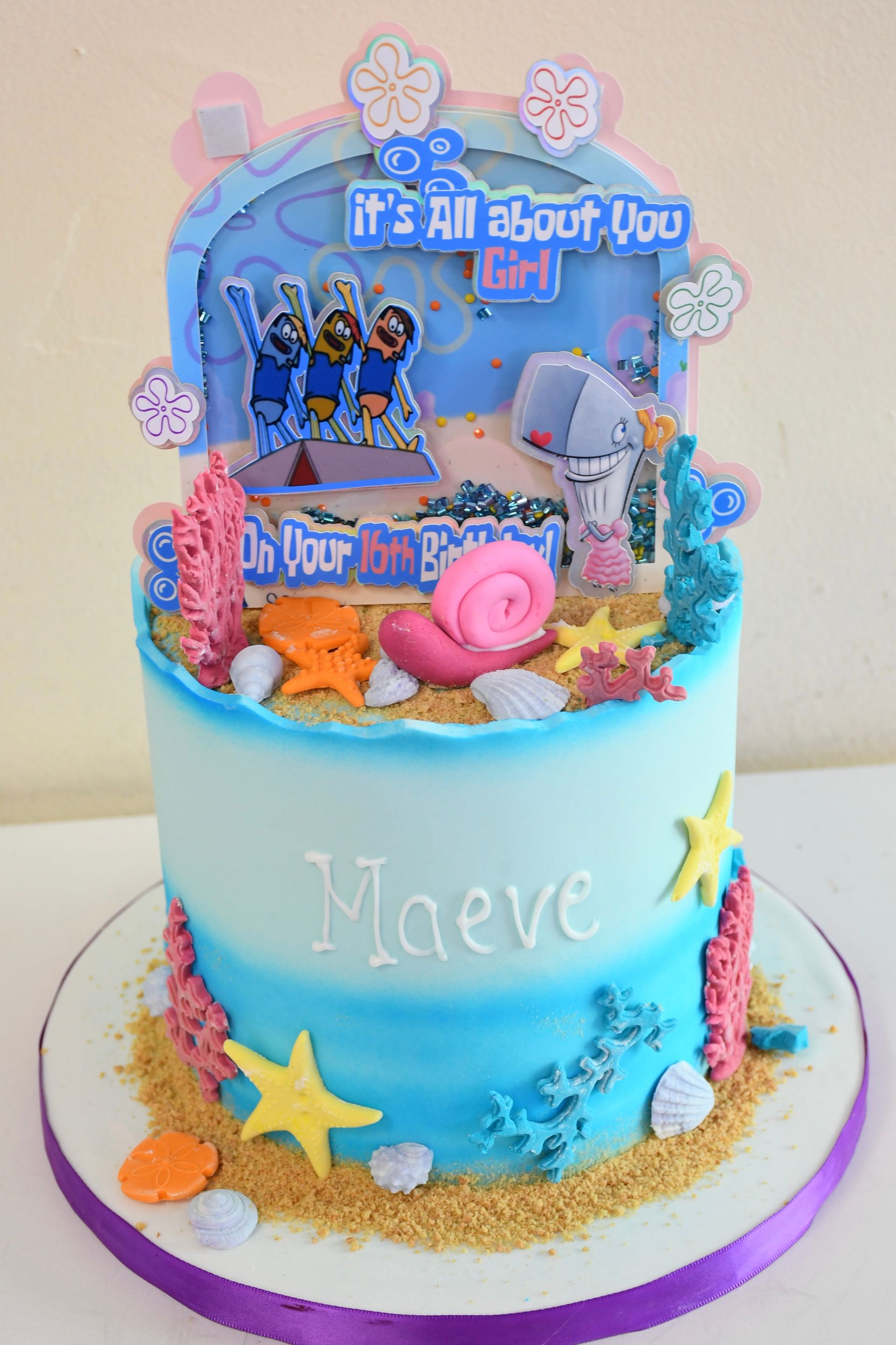 A blue cake with a spongebob cake topper is on a table.