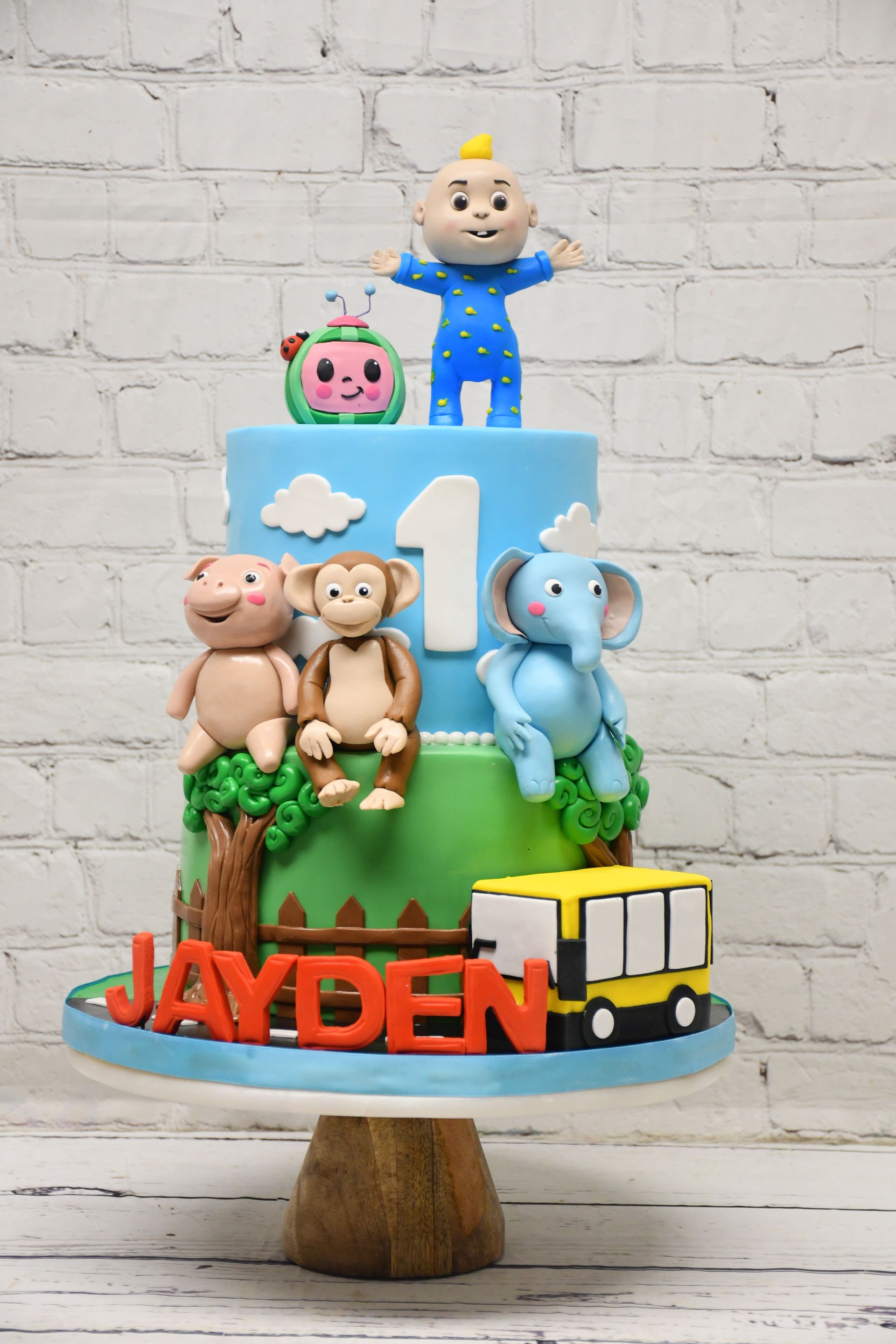 A cake with monkeys , elephants , and a train on it for a child 's first birthday.