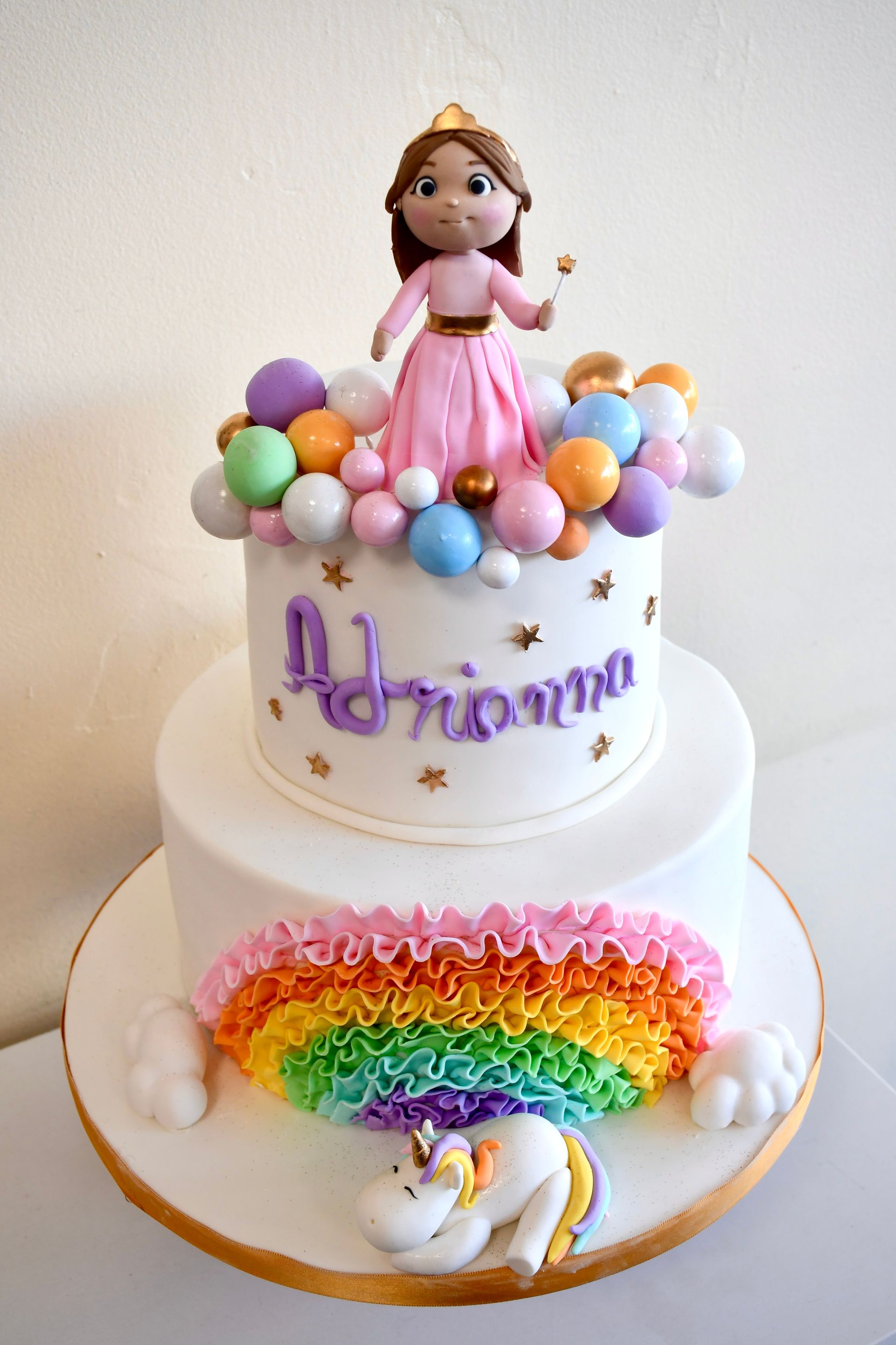 A birthday cake with a unicorn and a princess on top