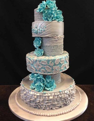 A wedding cake with blue flowers and pearls on it