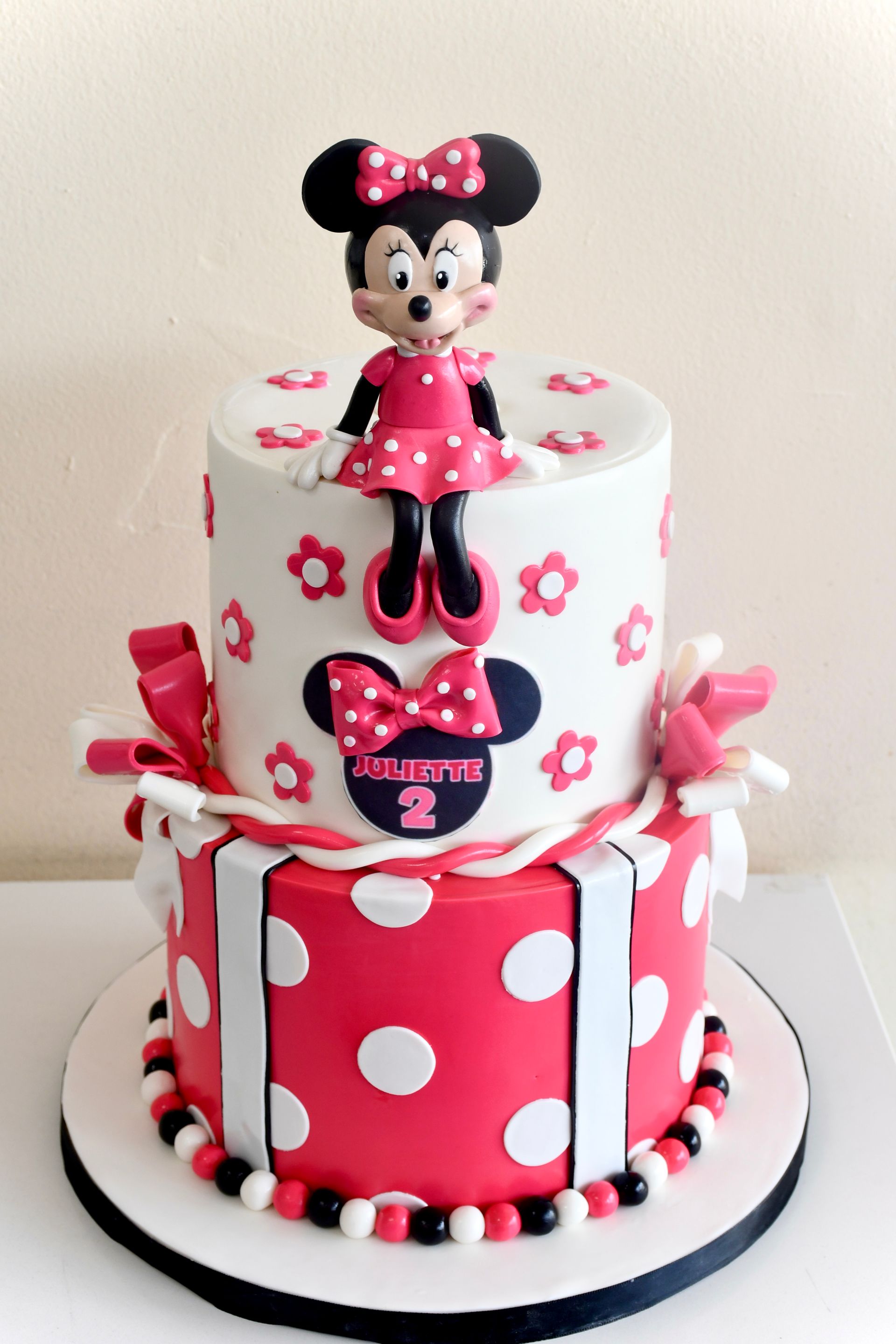 A red and white cake with minnie mouse on top