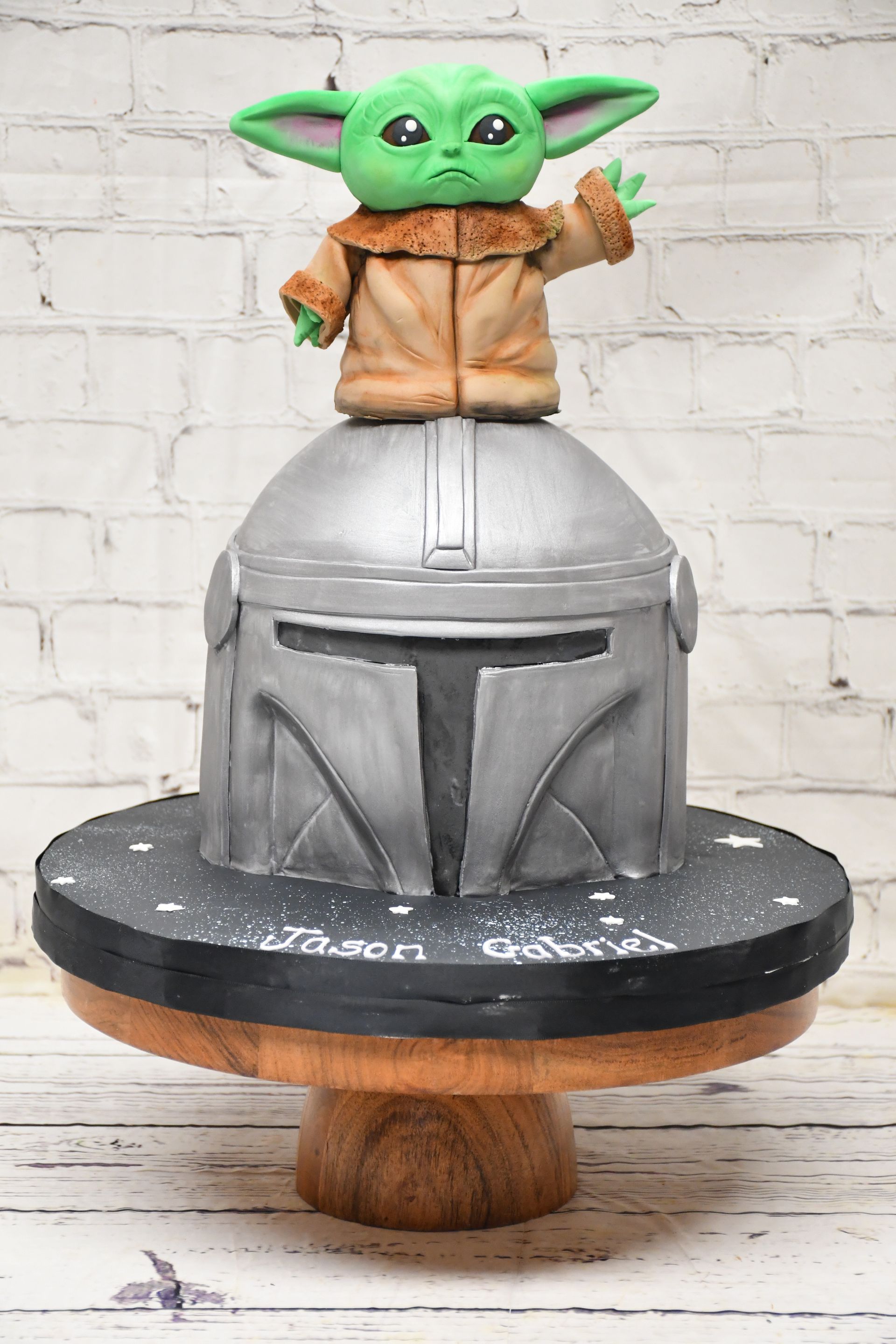 A baby yoda cake is sitting on top of a mandalorian helmet.