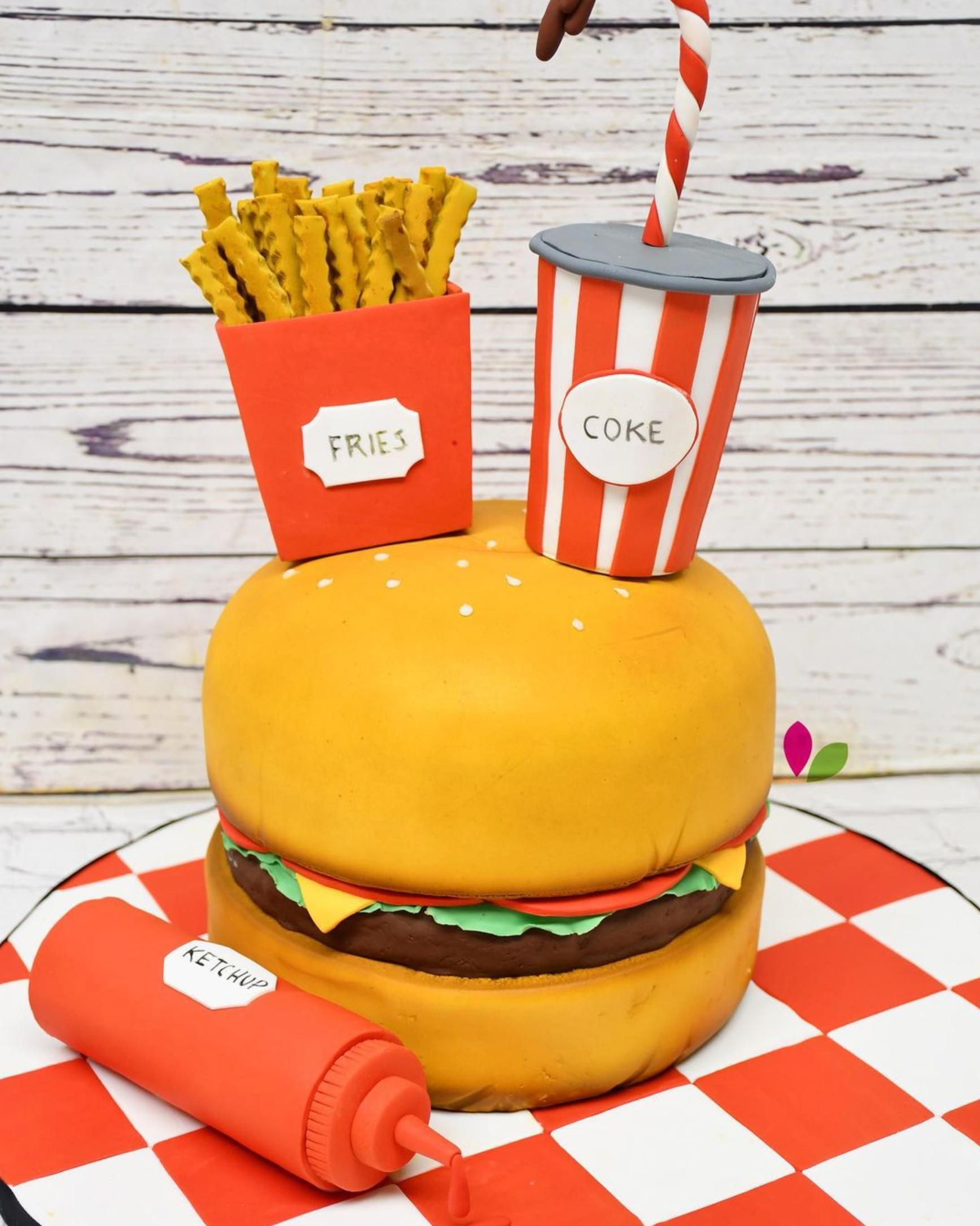 A cake in the shape of a hamburger with french fries and a coke