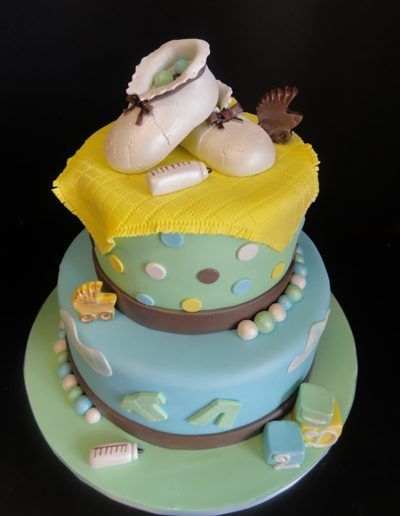 A baby shower cake with a pair of baby shoes on top