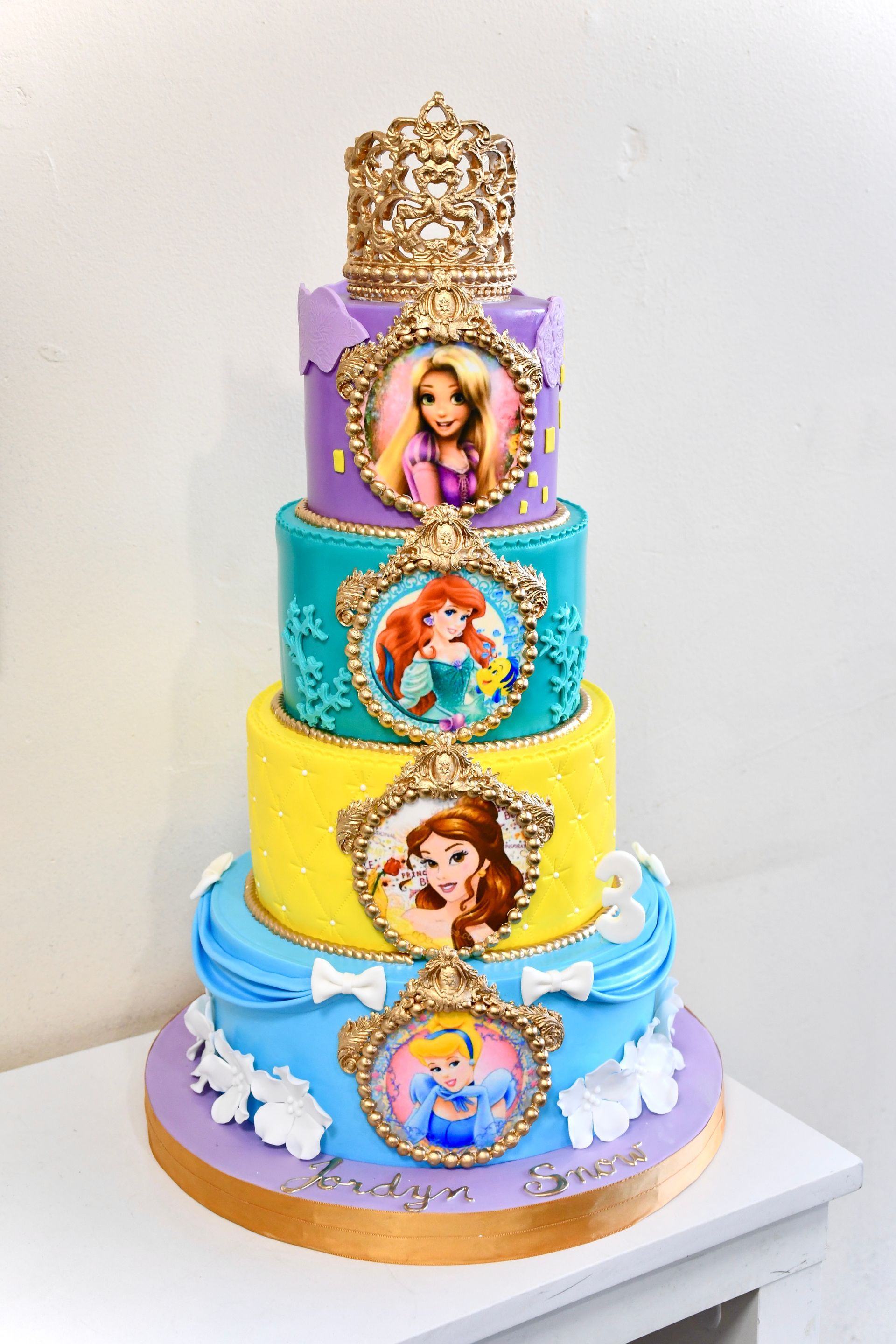 A colorful cake with princesses on it is sitting on a table.