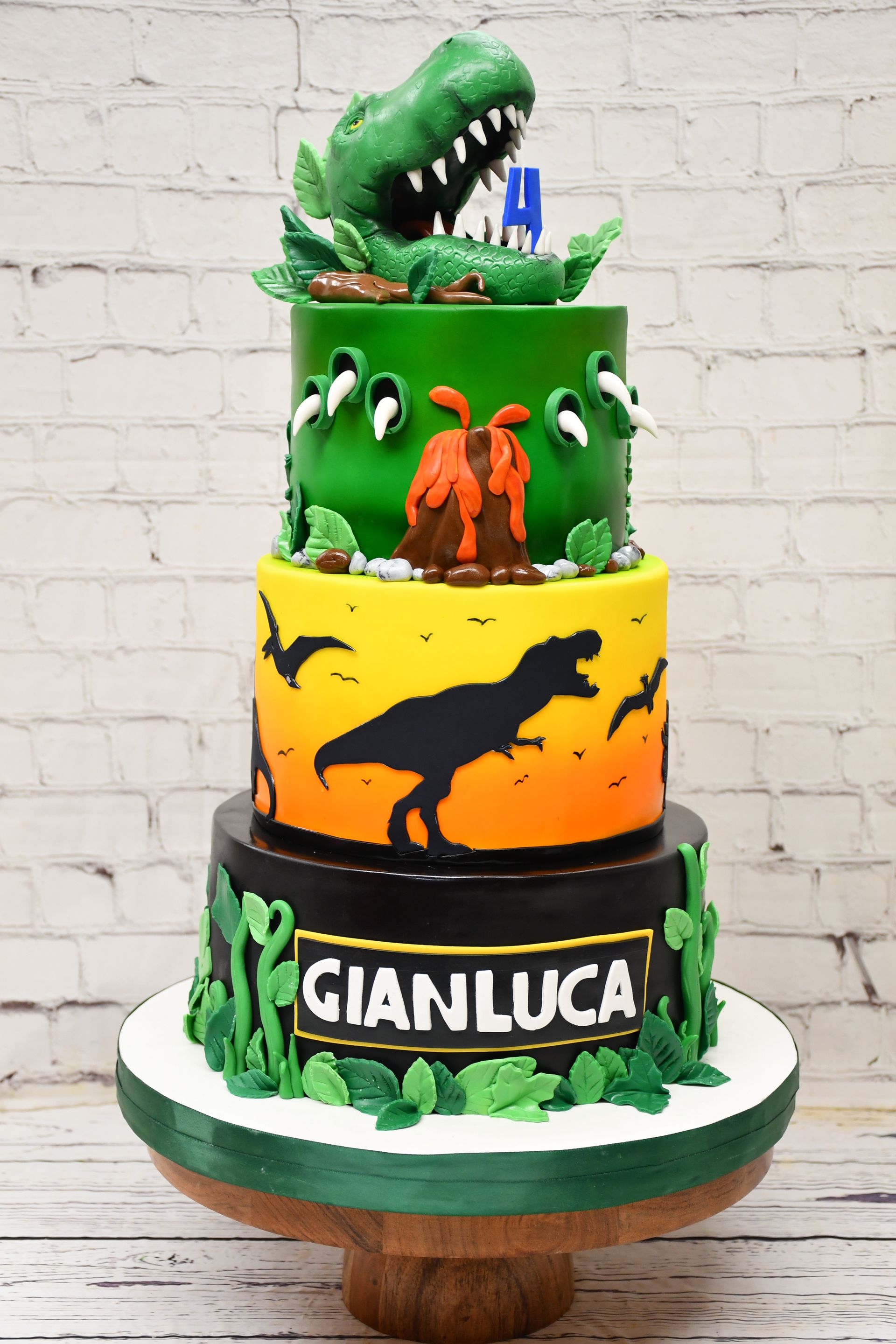 A cake with a dinosaur on top of it and the name gianluca on it