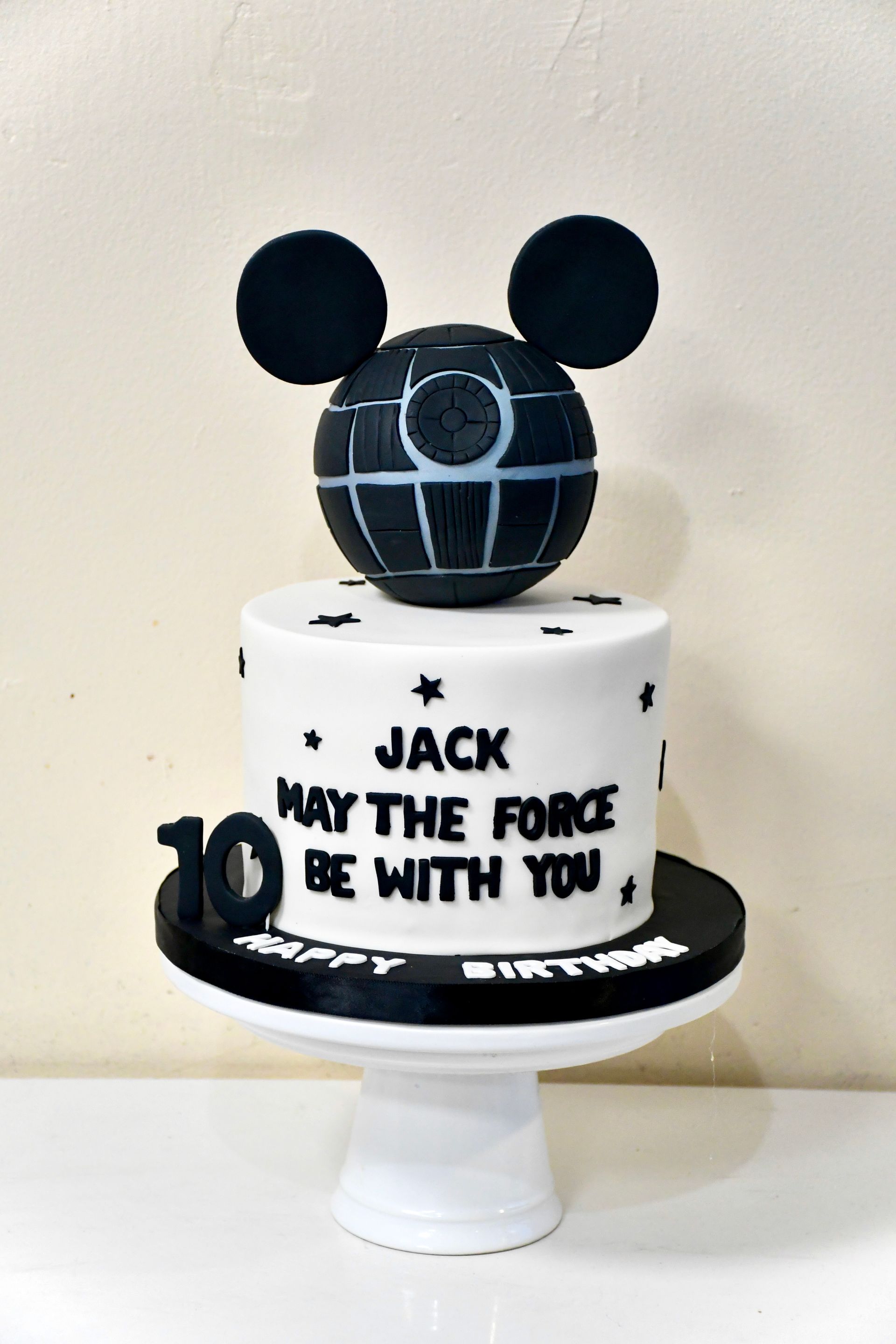 A black and white cake with a mickey mouse head on top of it.