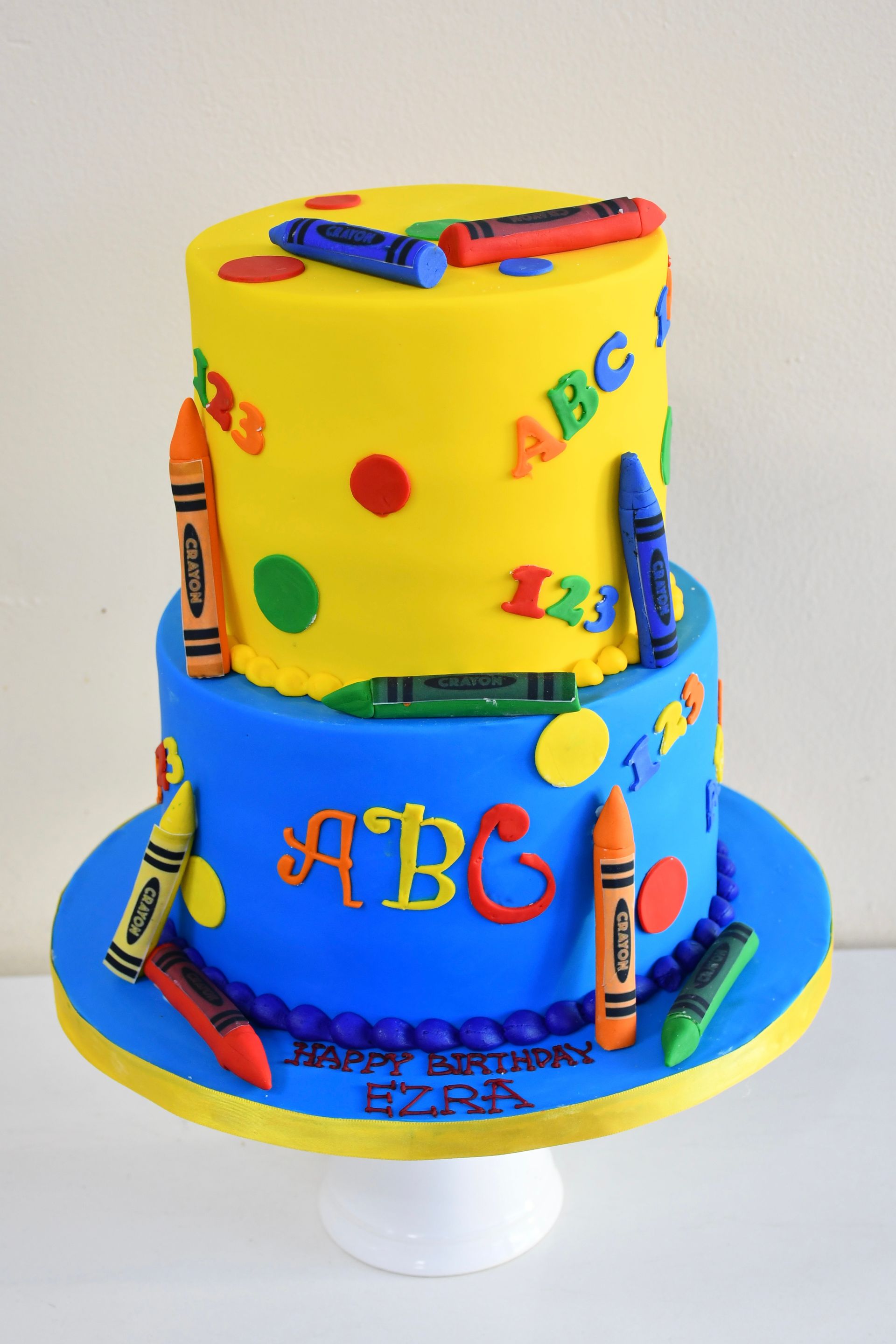 A birthday cake with crayons and the letters abc on it
