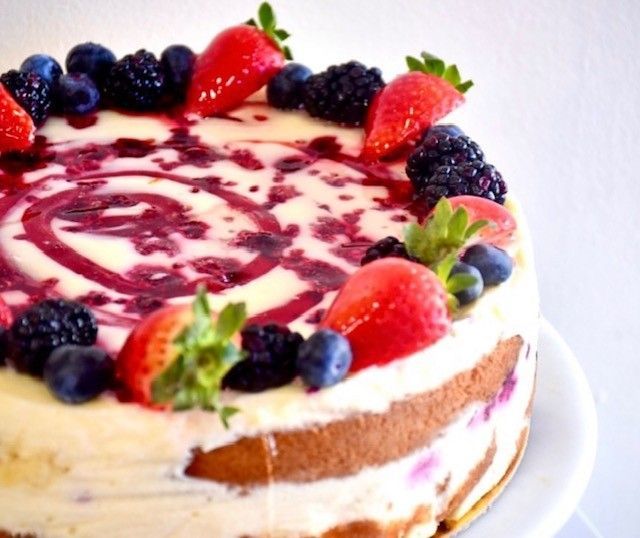 A cake with strawberries blueberries and blackberries on top