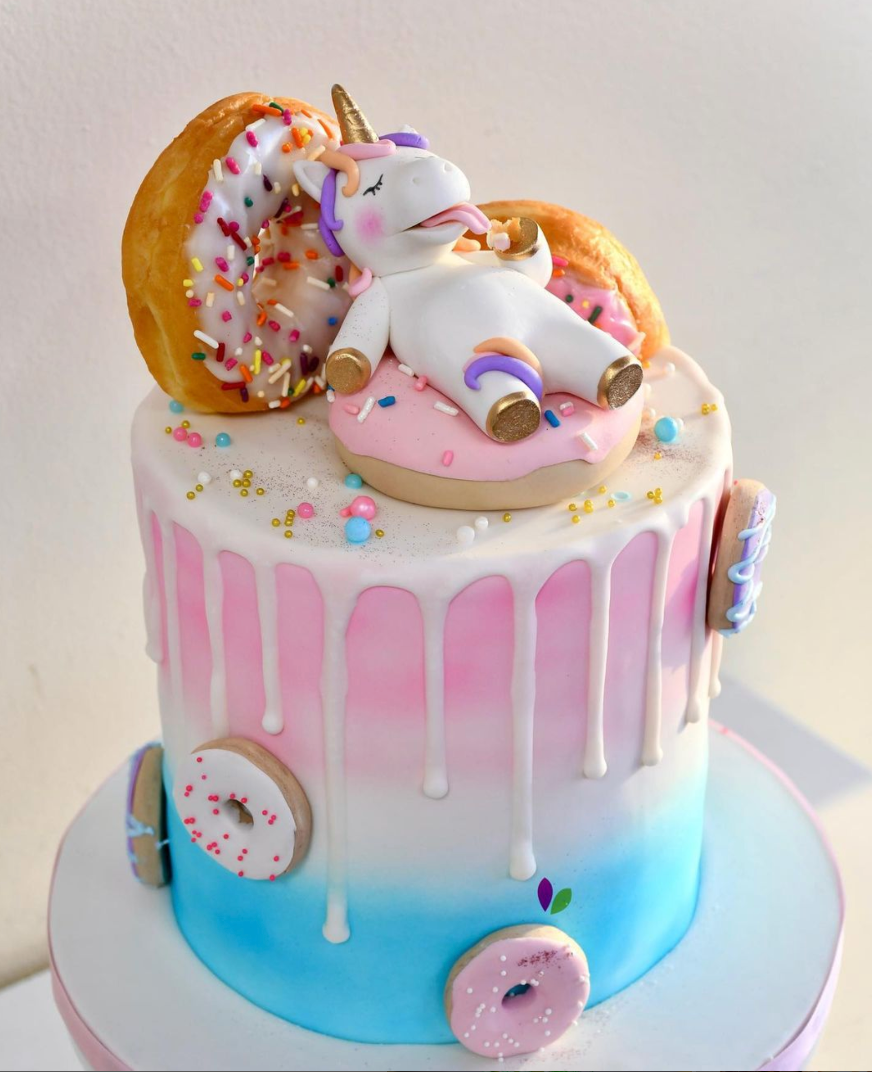 A cake with a unicorn laying on top of a donut