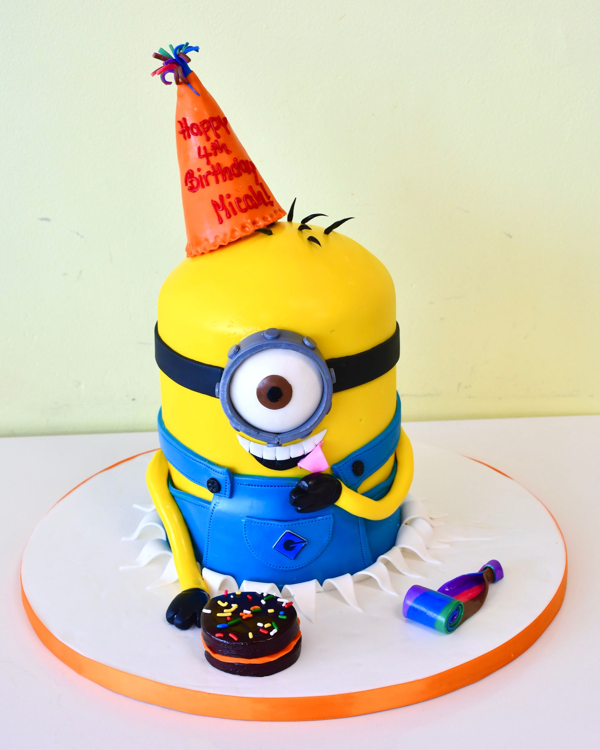A birthday cake with a minion wearing a party hat