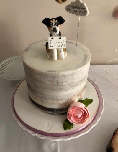 A cake with a dog holding a sign that says i loved her first