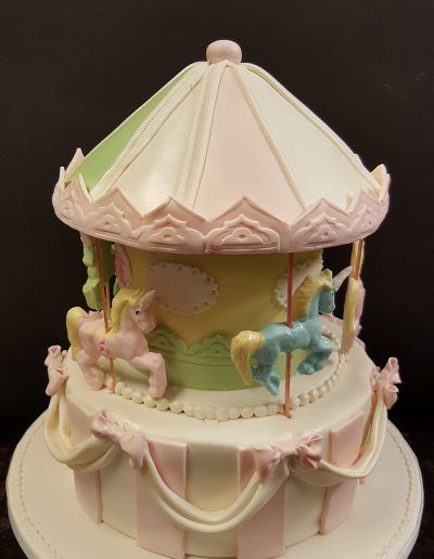 A cake that looks like a merry go round with ponies on it