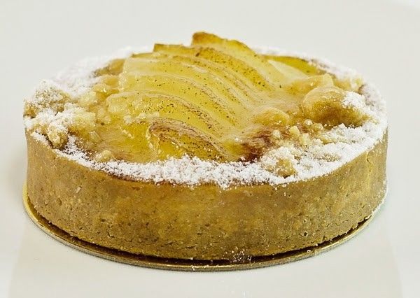 A close up of a pie with powdered sugar on top on a white surface.