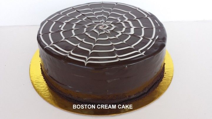 A chocolate cake with white frosting is sitting on a gold plate.