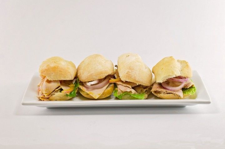 A white plate topped with four sandwiches on a white background.