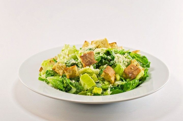 A white plate topped with a salad of lettuce , croutons and cheese.
