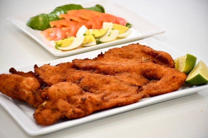 A plate of fried meat next to a plate of vegetables
