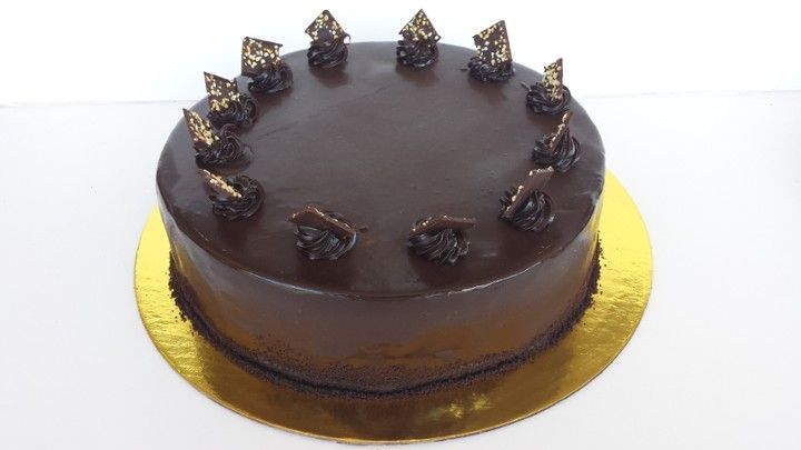 A chocolate cake is sitting on a gold plate on a table.