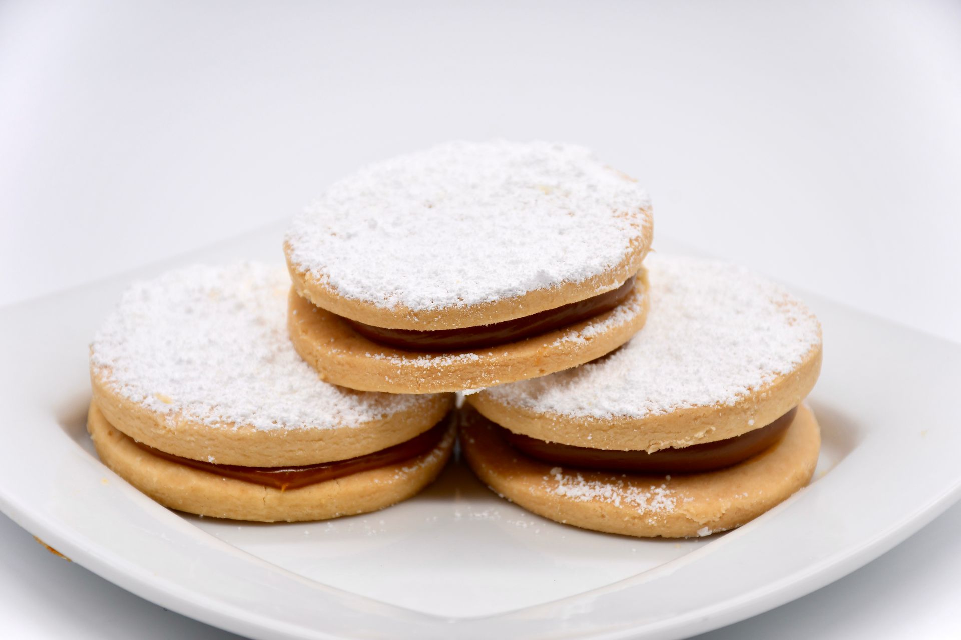 Three cookies are stacked on top of each other on a white plate.