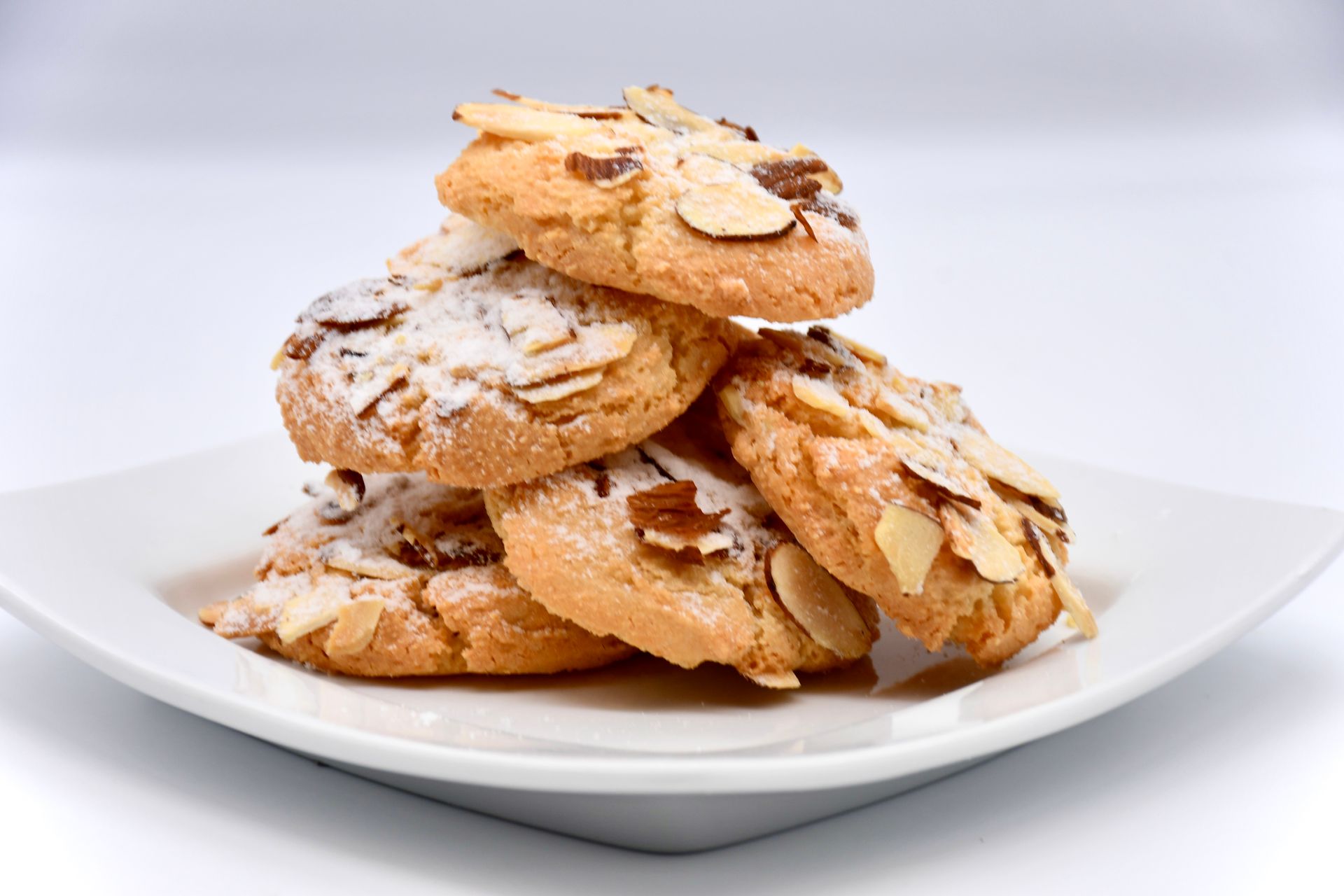 A white plate topped with a stack of almond cookies