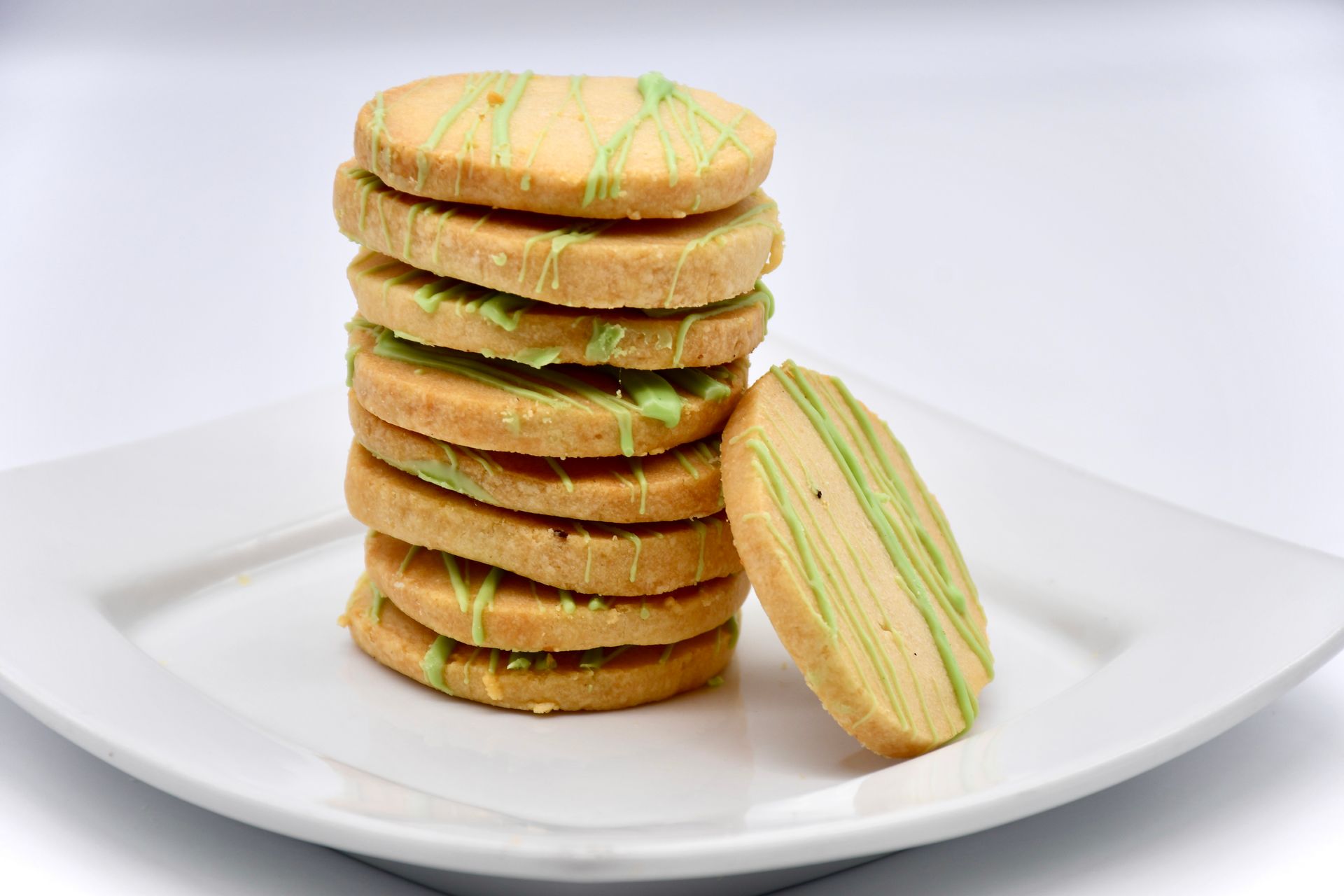 A stack of cookies with green frosting on a white plate.