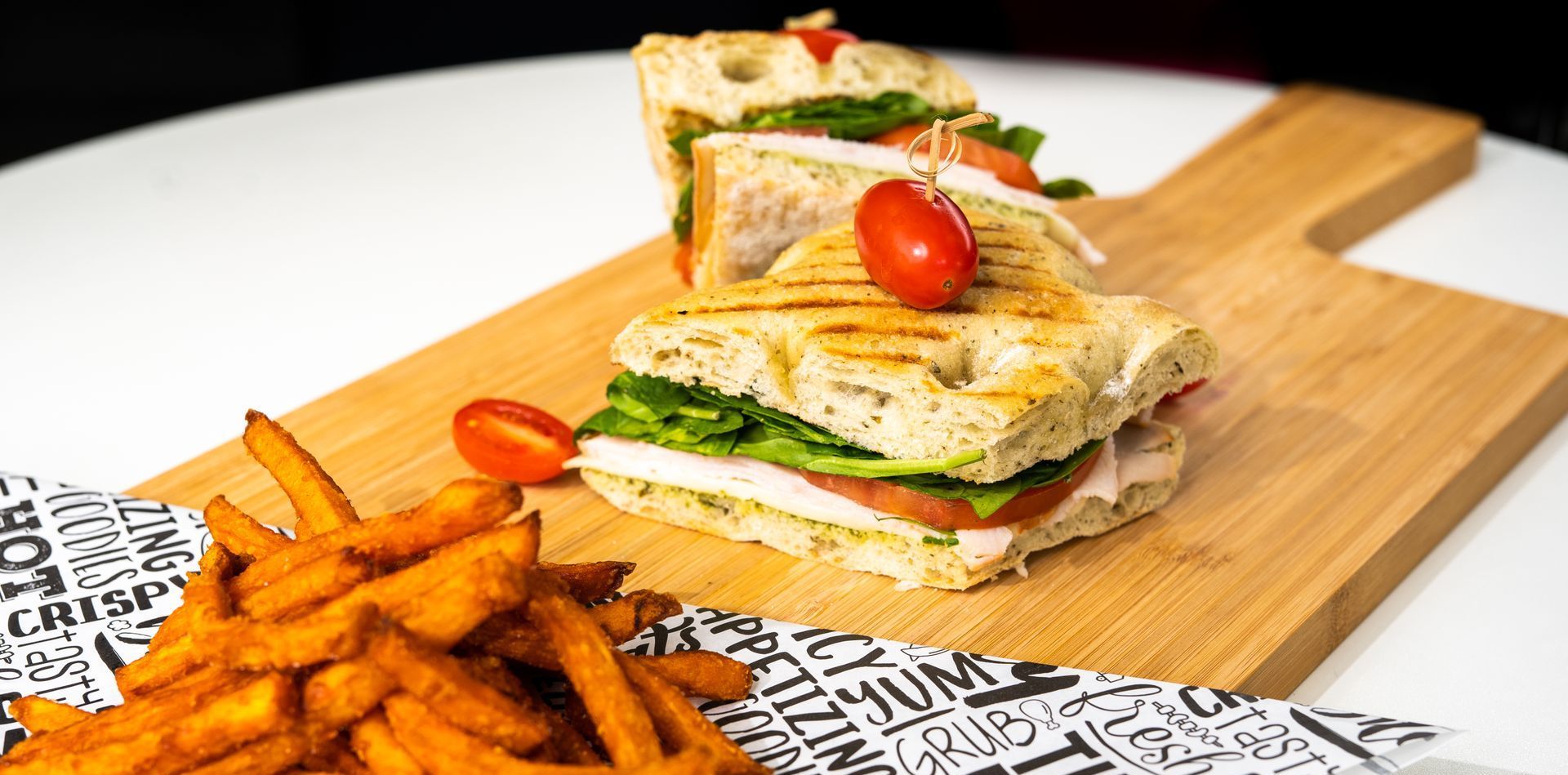 A sandwich and french fries on a wooden cutting board on a table.