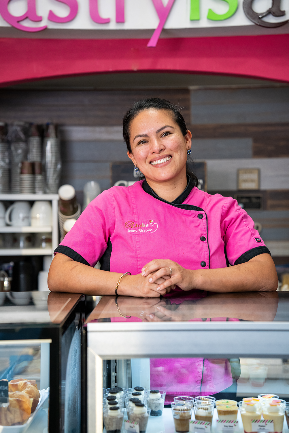 A woman in a pink shirt is standing behind a counter in a restaurant.