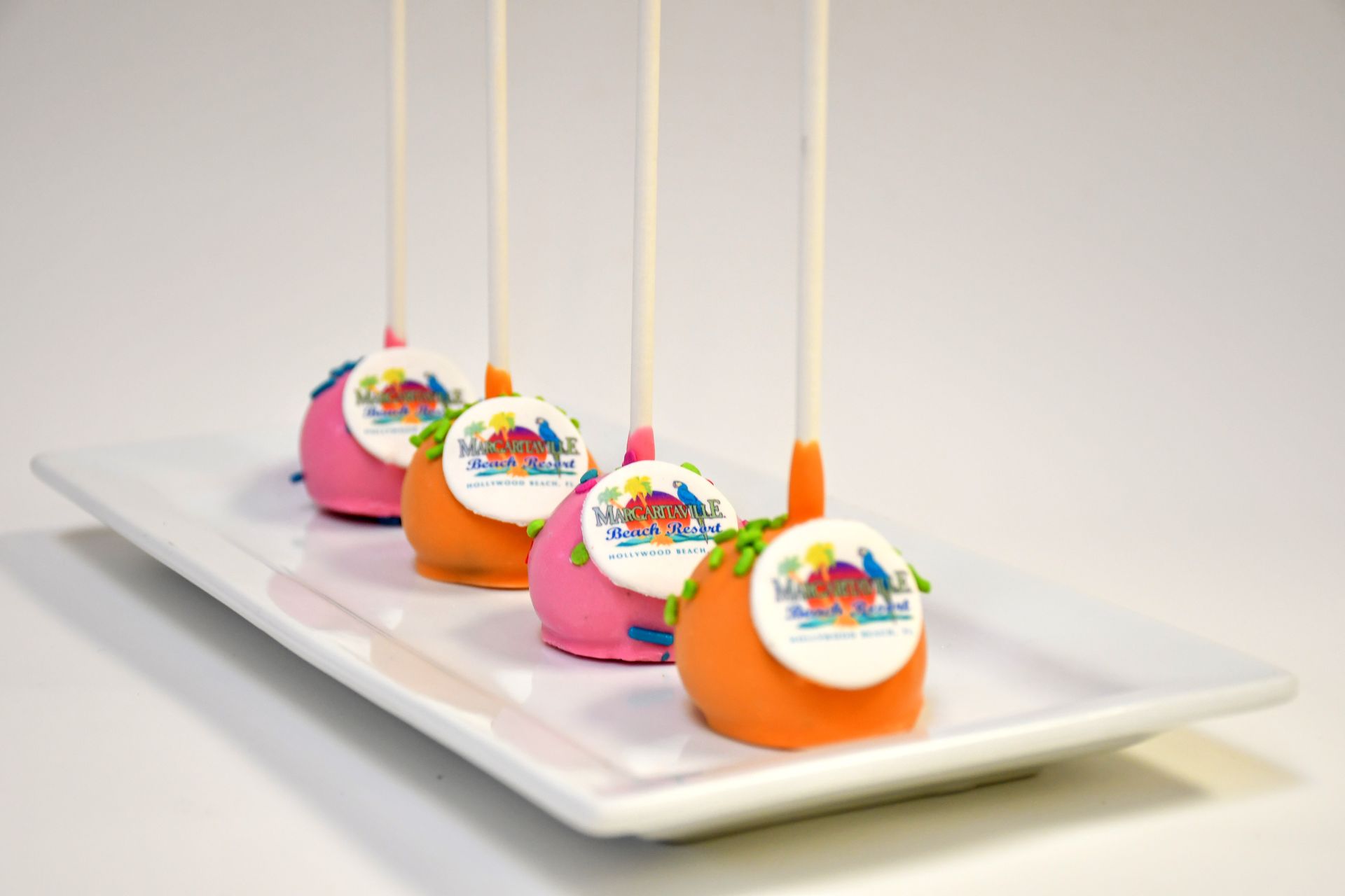 Four cake pops are sitting on a white plate.