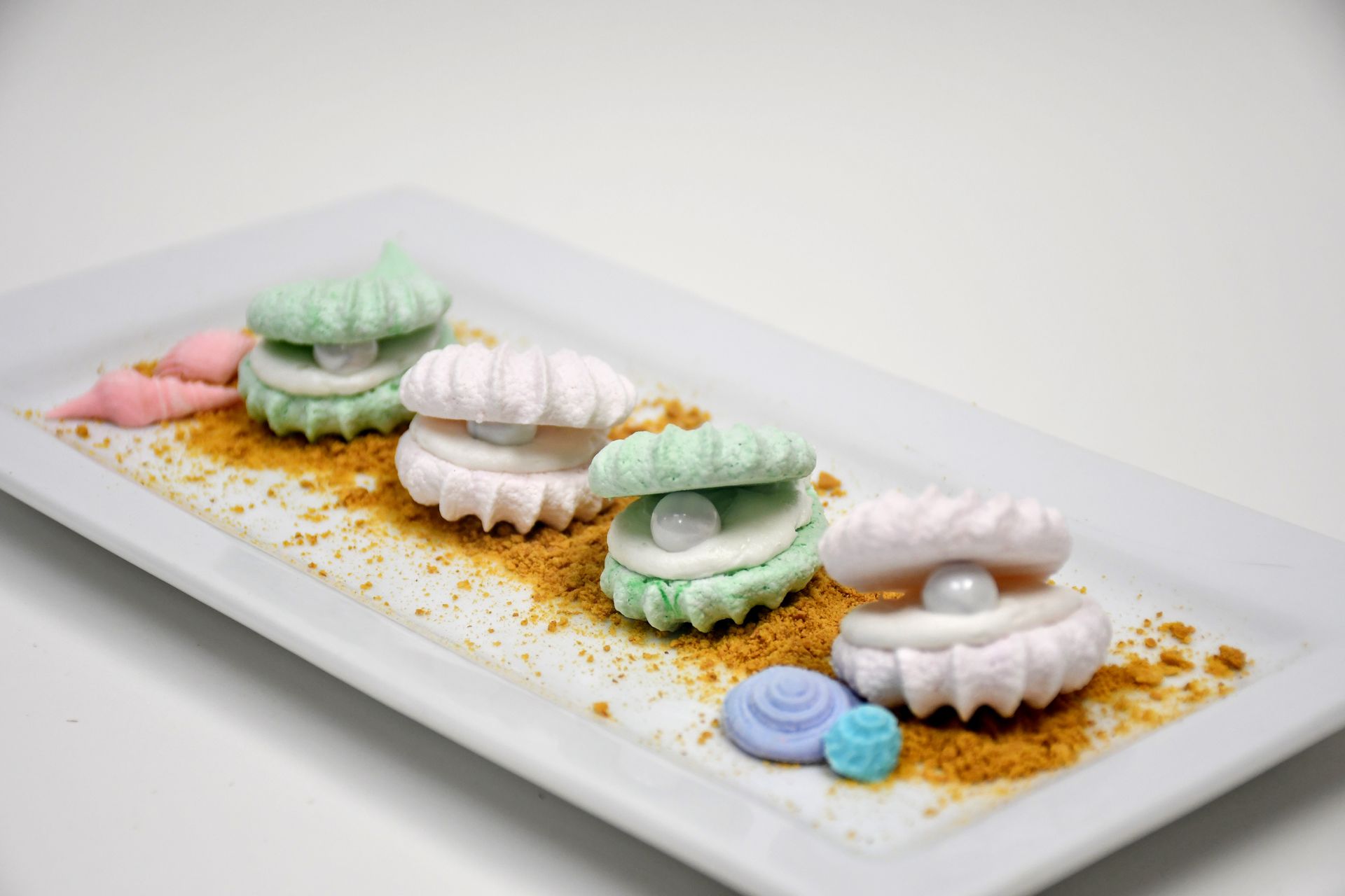 A white plate topped with marshmallows in the shape of seashells.