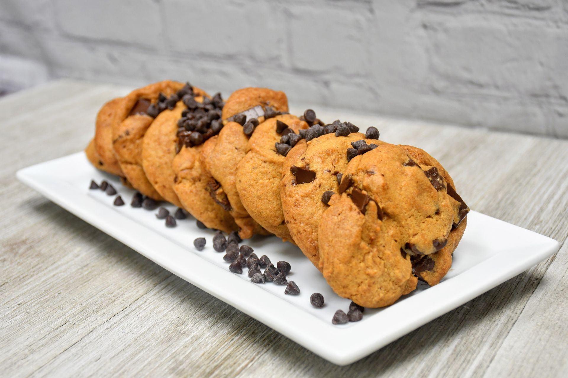 A white plate topped with chocolate chip cookies on a wooden table.