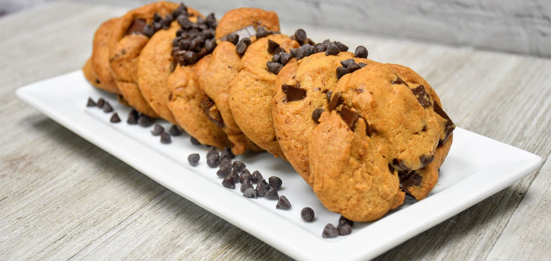A white plate topped with chocolate chip cookies on a table.
