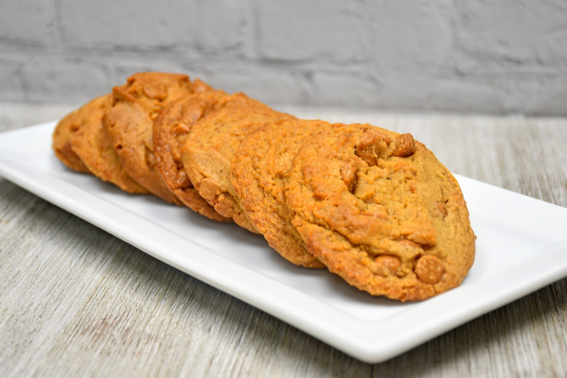 A white plate topped with peanut butter cookies on a wooden table.