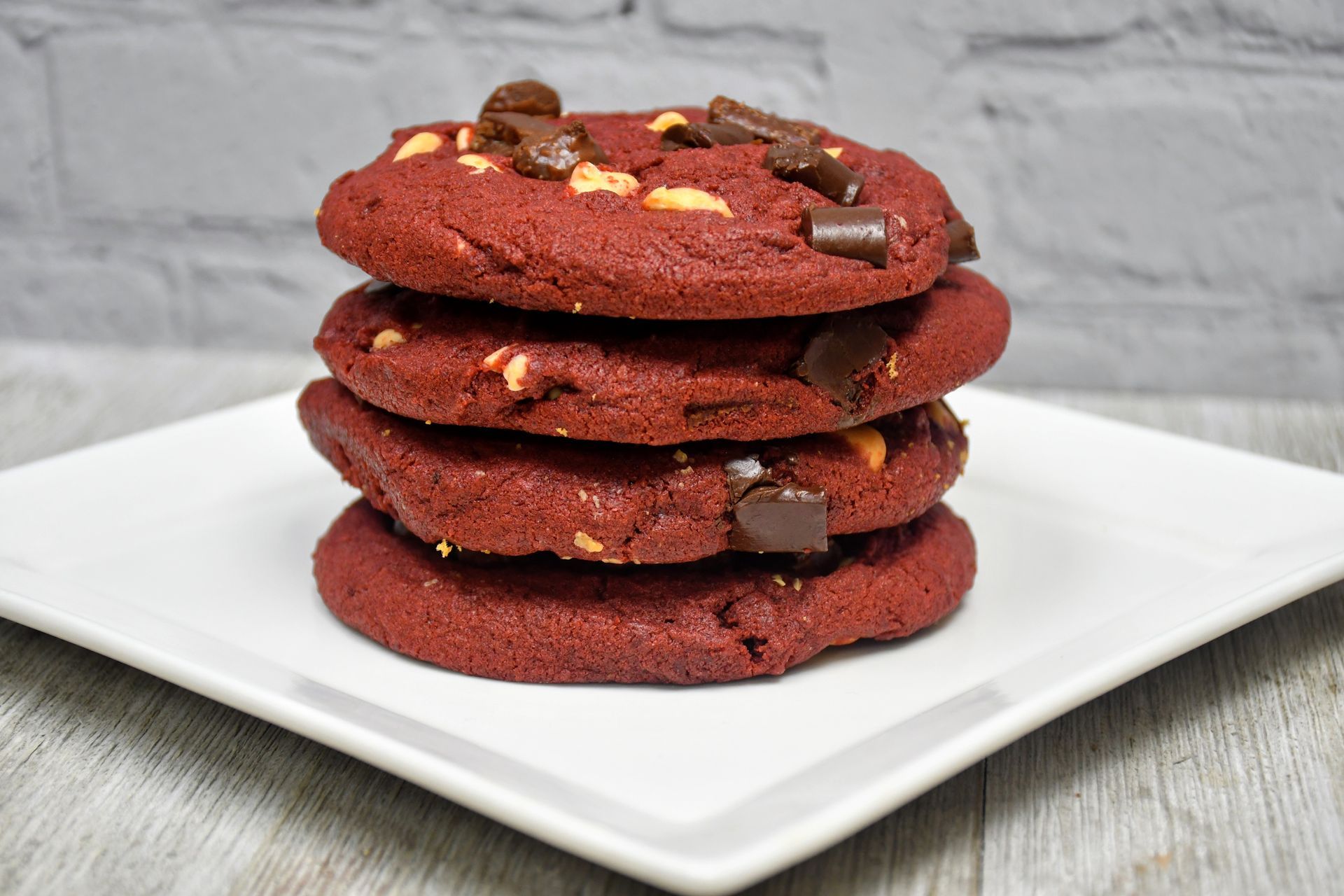 A stack of red velvet cookies with chocolate chips on a white plate.