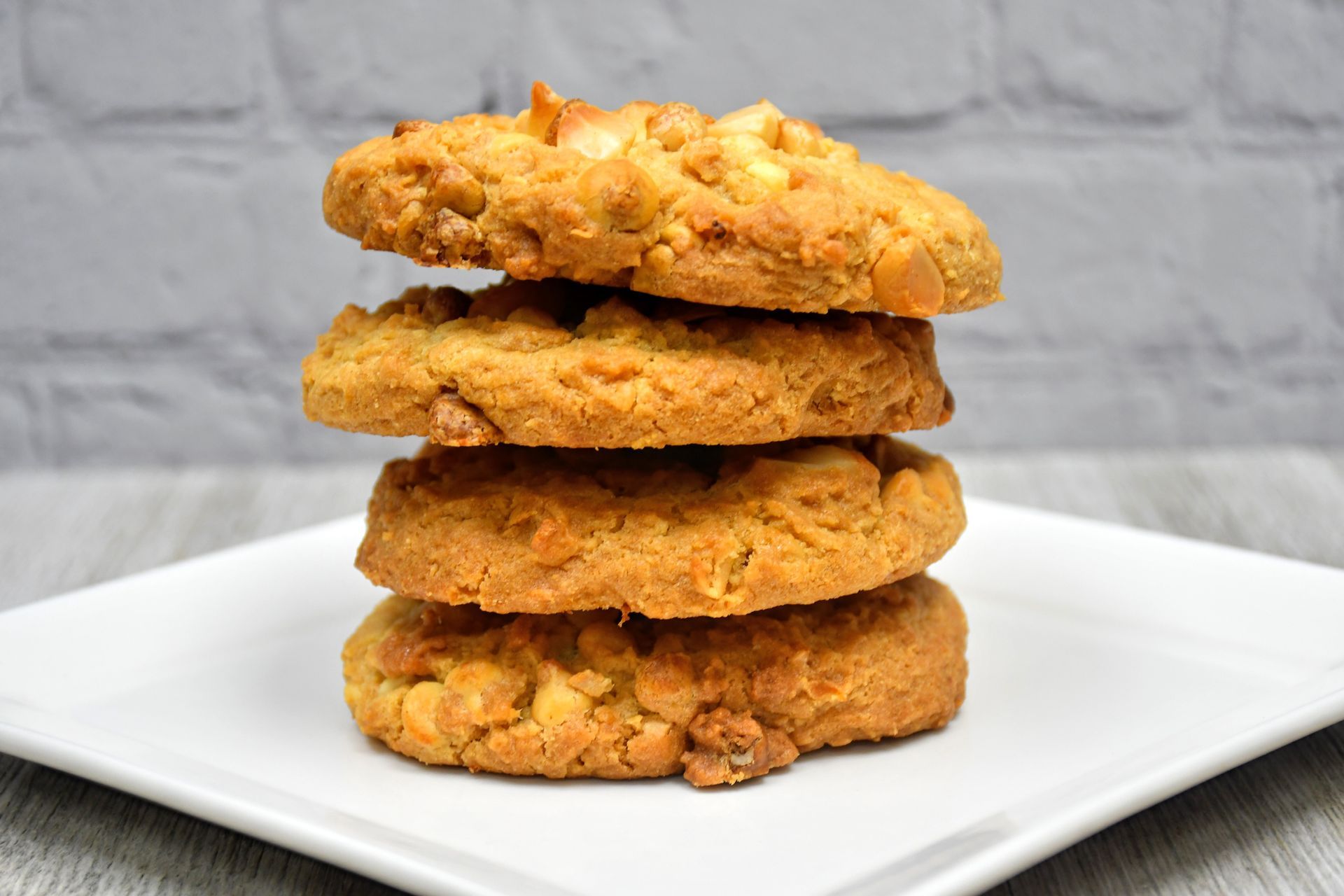 Four cookies are stacked on top of each other on a white plate.