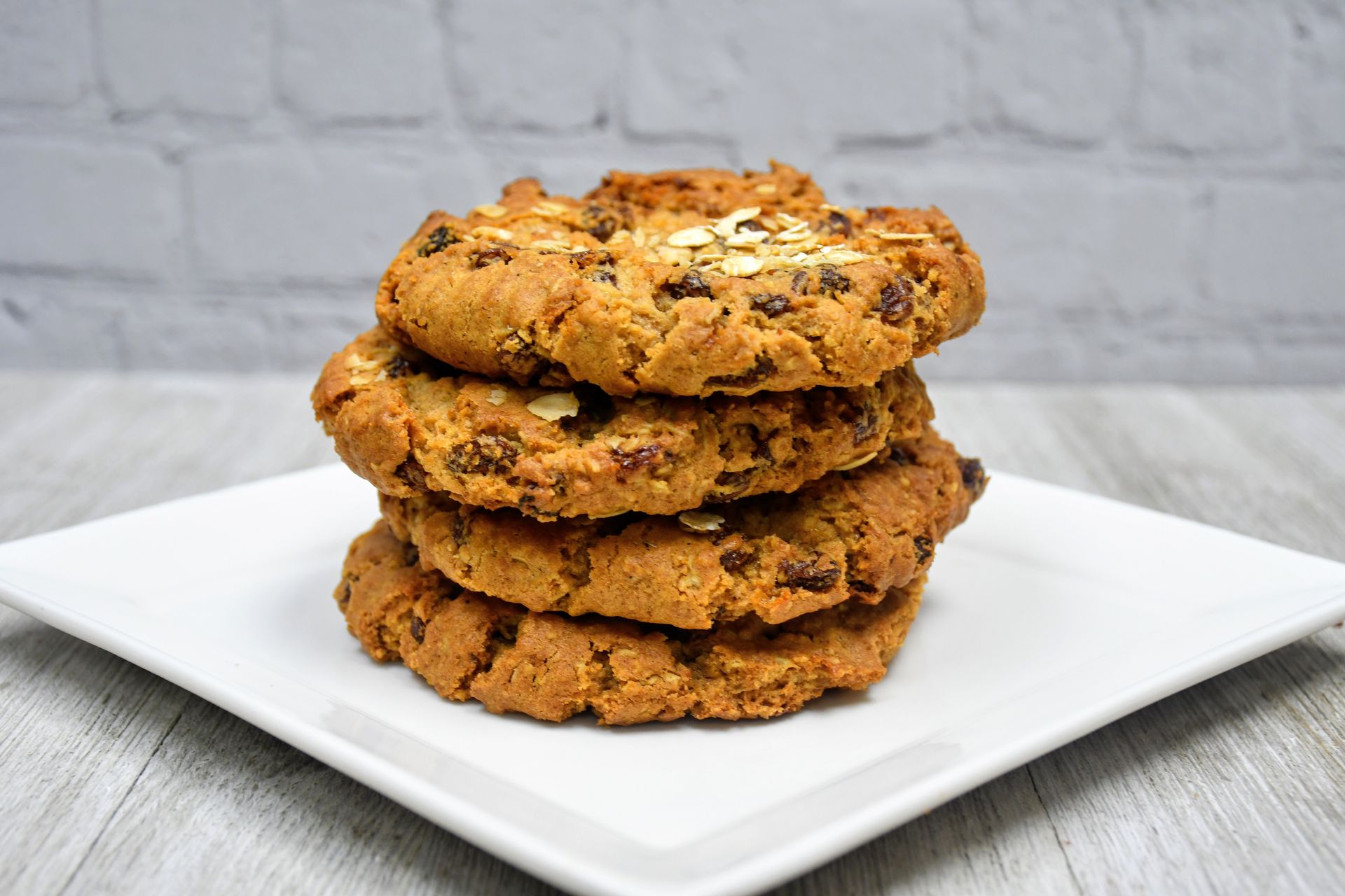 Four cookies are stacked on top of each other on a white plate.
