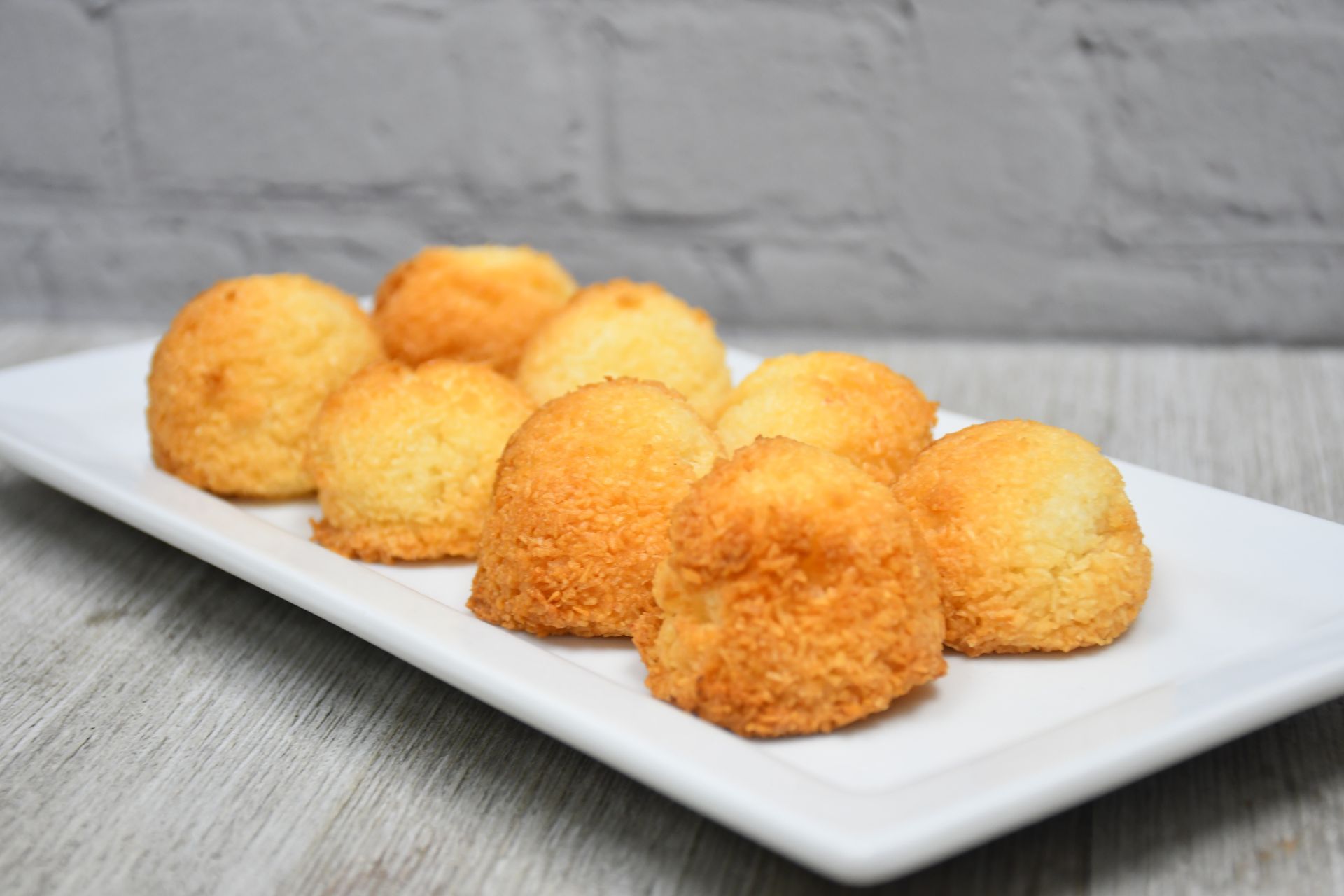 A white plate topped with coconut cookies on a wooden table.
