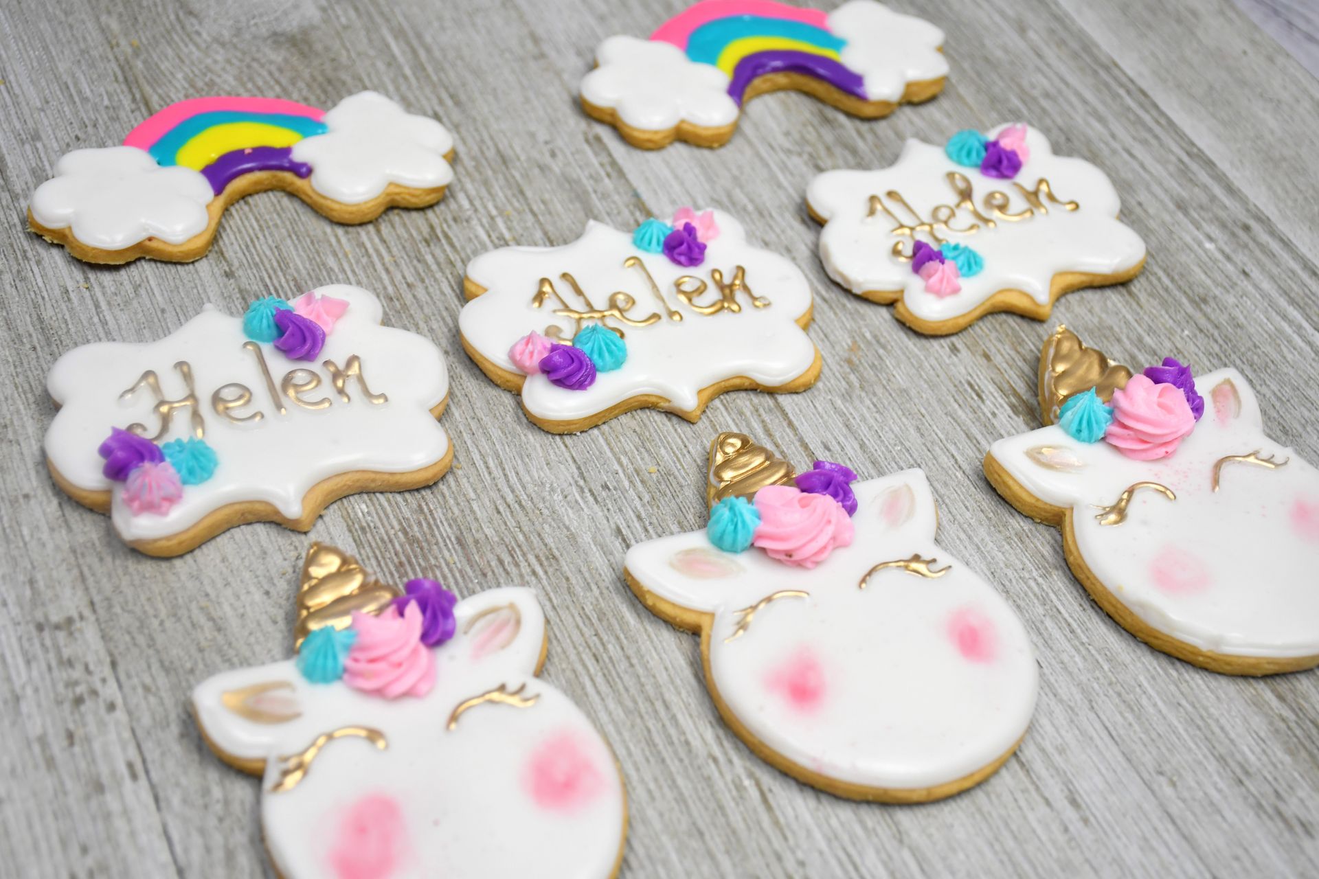 A bunch of unicorn cookies are sitting on a wooden table.