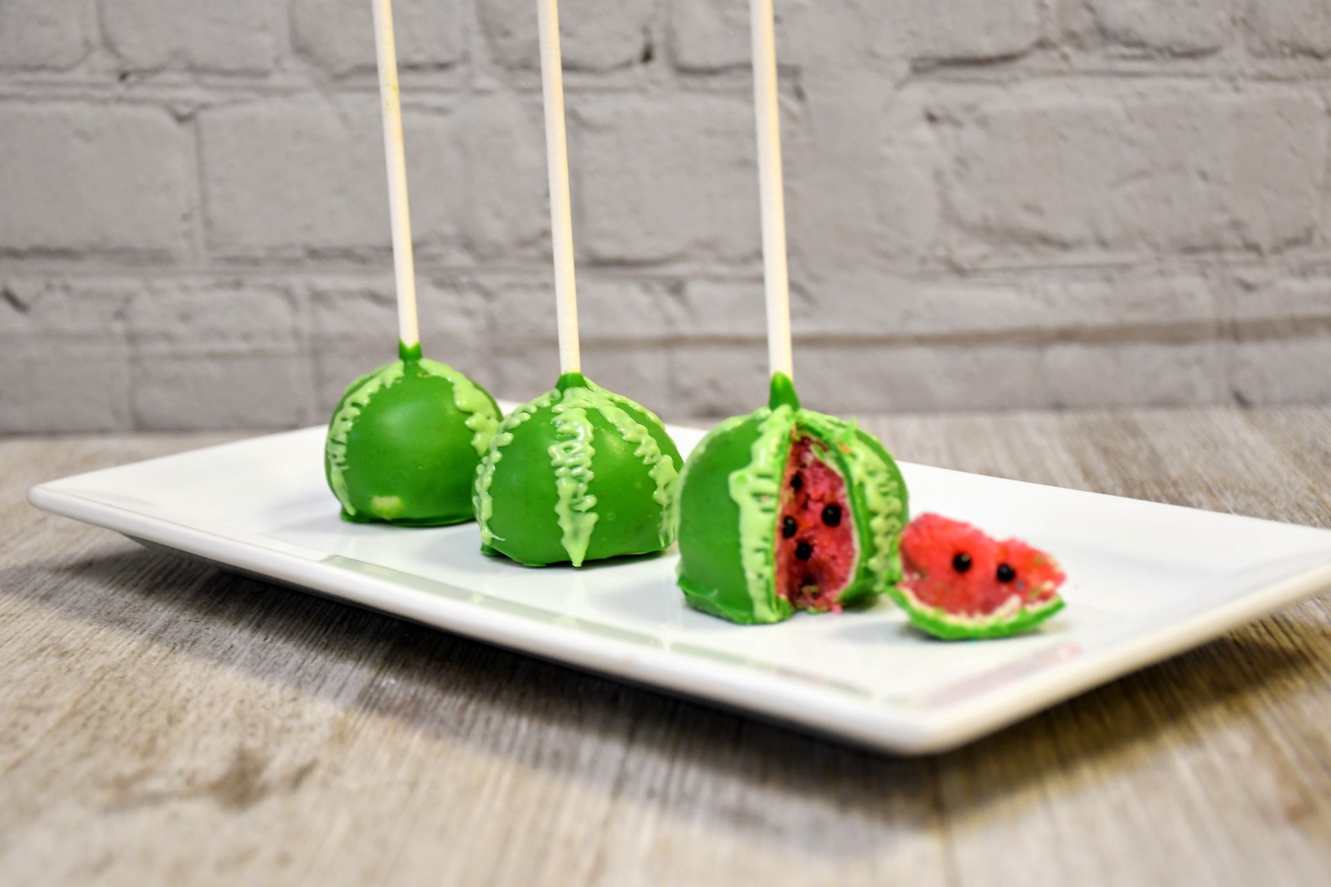 A white plate topped with watermelon cake pops and a slice of watermelon.