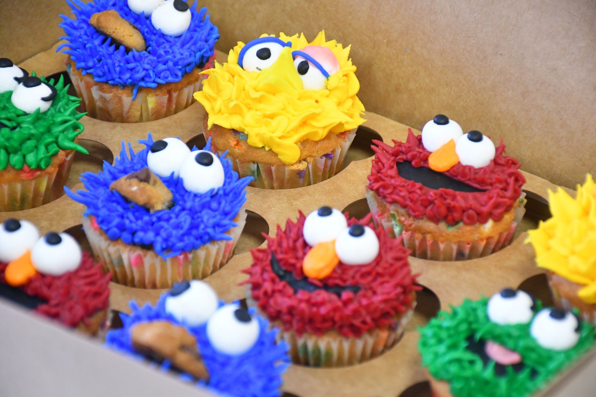A box of sesame street cupcakes with elmo and cookie monster on them