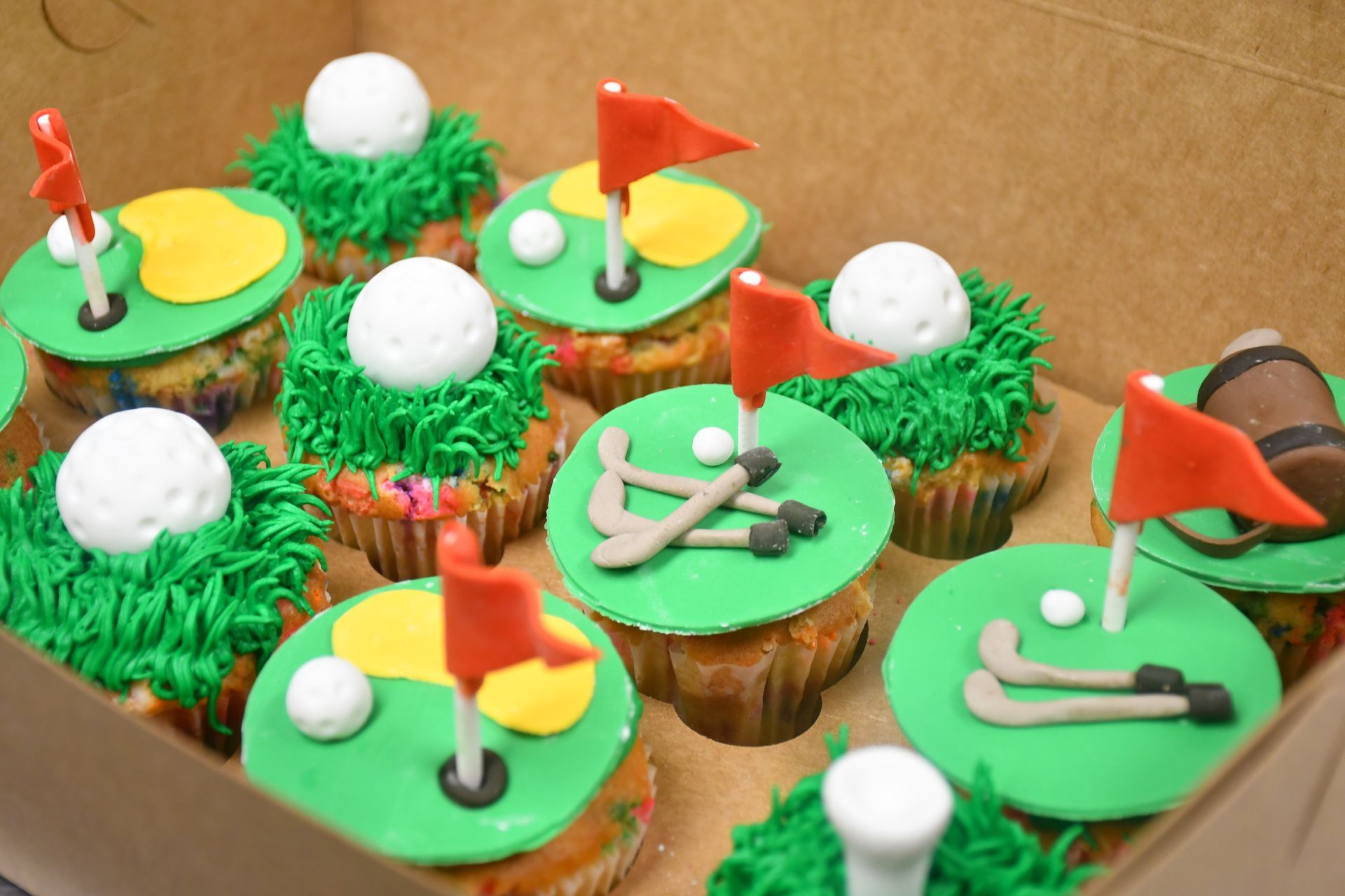 A box of cupcakes decorated to look like a golf course