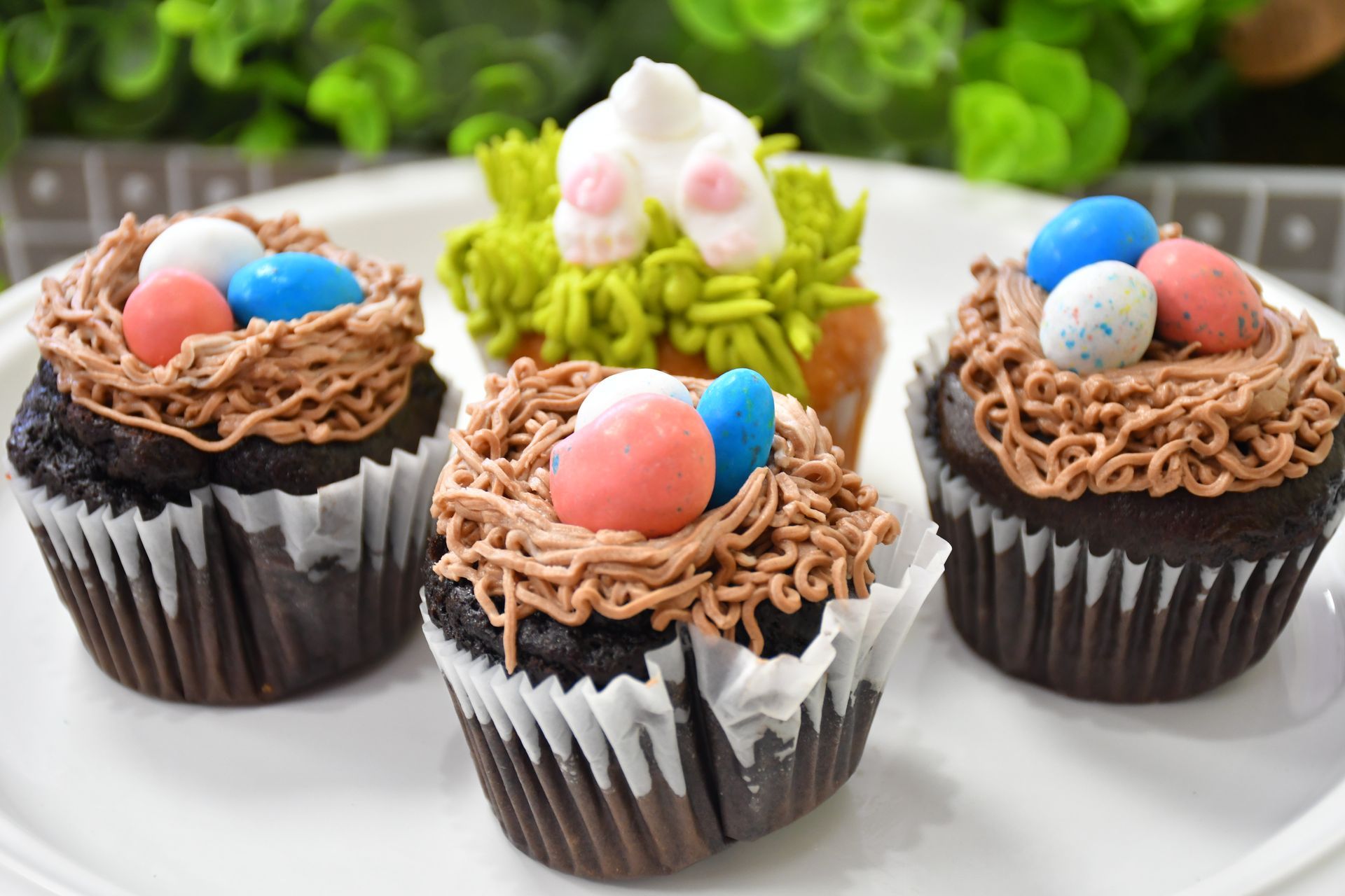A white plate topped with four chocolate cupcakes decorated for easter.